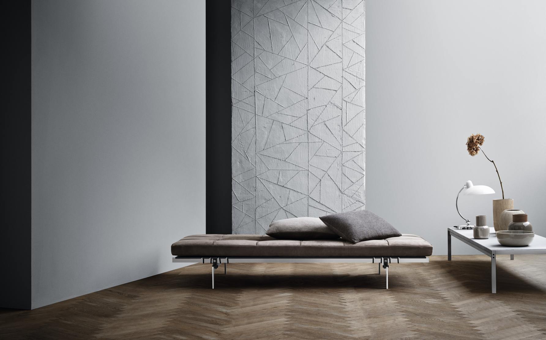 Elegante PK80 Liege von Fritz Hansen mit braunem Lederbezug und zwei Kissen im modernen Wohnzimmer.