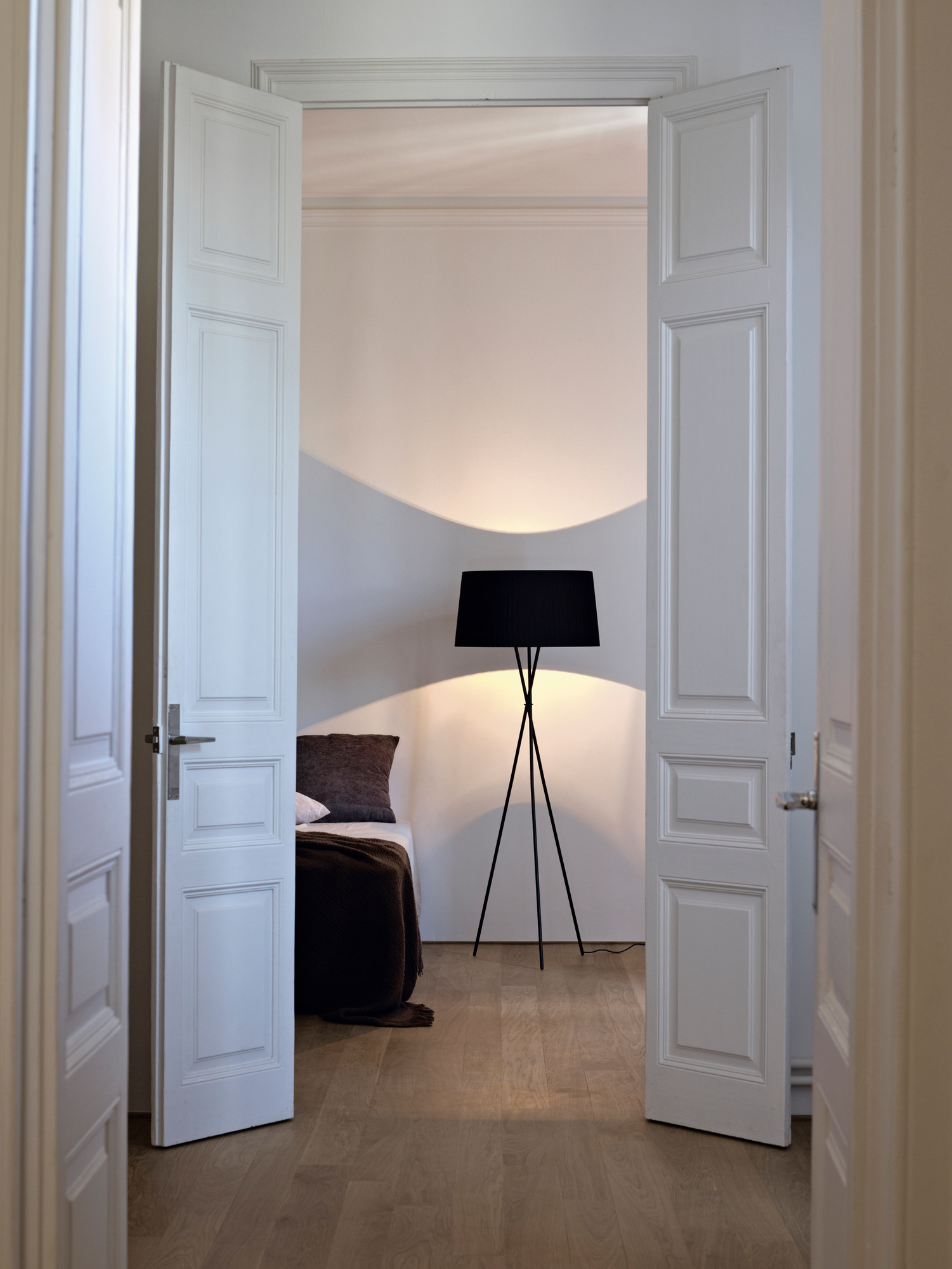 Tripode G5 Stehleuchte von Santa & Cole in einem Schlafzimmer mit geöffneten weißen Türen.
