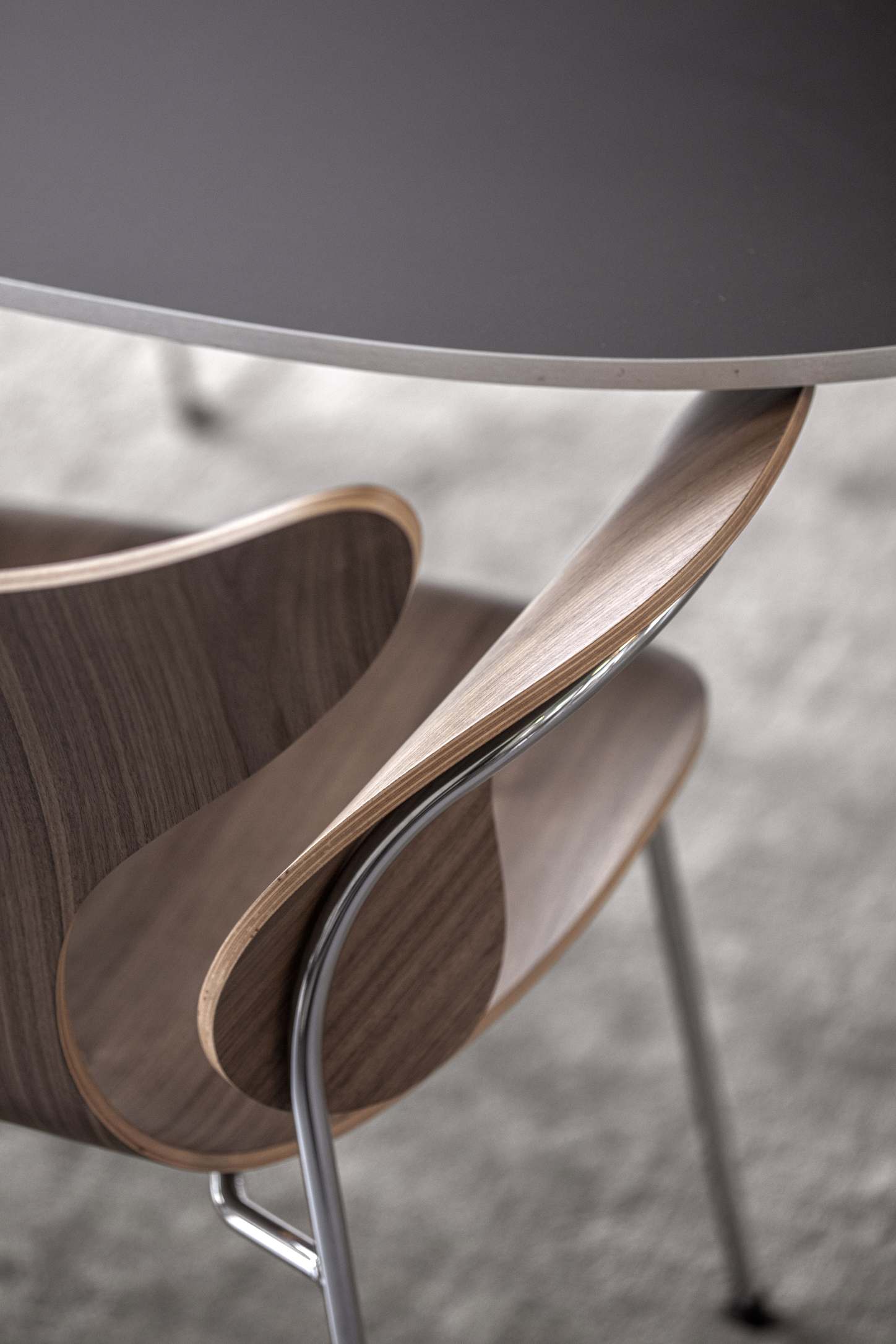 Detailaufnahme des Fritz Hansen Lily Armlehnstuhls 3208 mit Holzschale und verchromtem Stahlgestell, modernes Design.