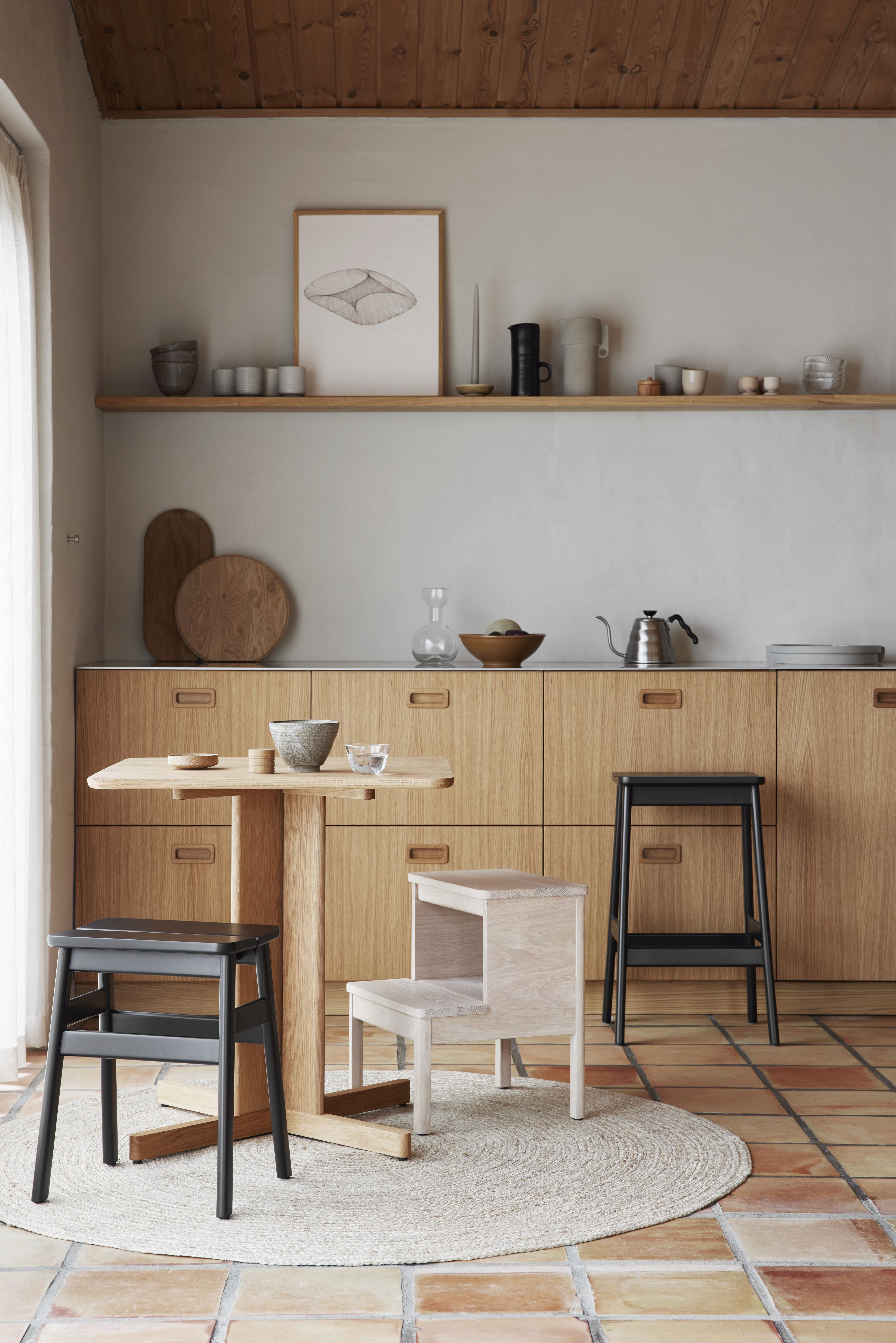 Angle Barhocker von Form & Refine, schwarz gebeizt, an einem Holztisch in modernem Interieur.