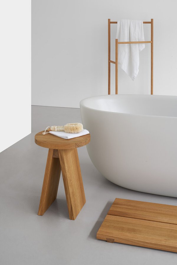 Badezimmer-Szene mit e15 EK04 Handtuchhalter aus Holz, Badewanne, Hocker und Badematte für ein stilvolles Ambiente.