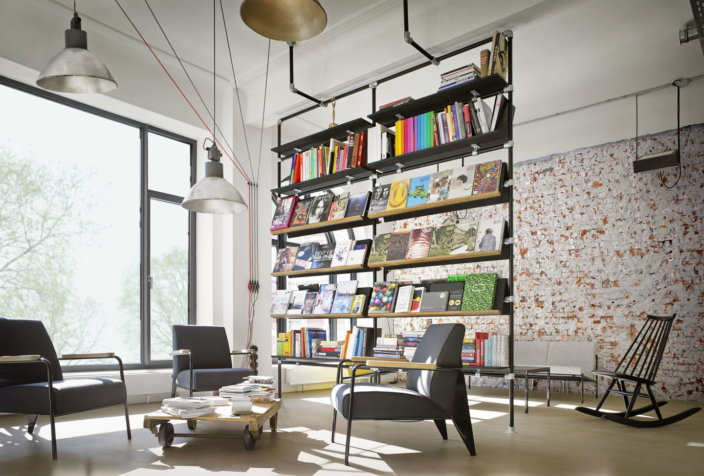 Innenaufnahme mit drei Fauteuil De Salon Sesseln von Vitra, Bücherregal und Loft-Atmosphäre.