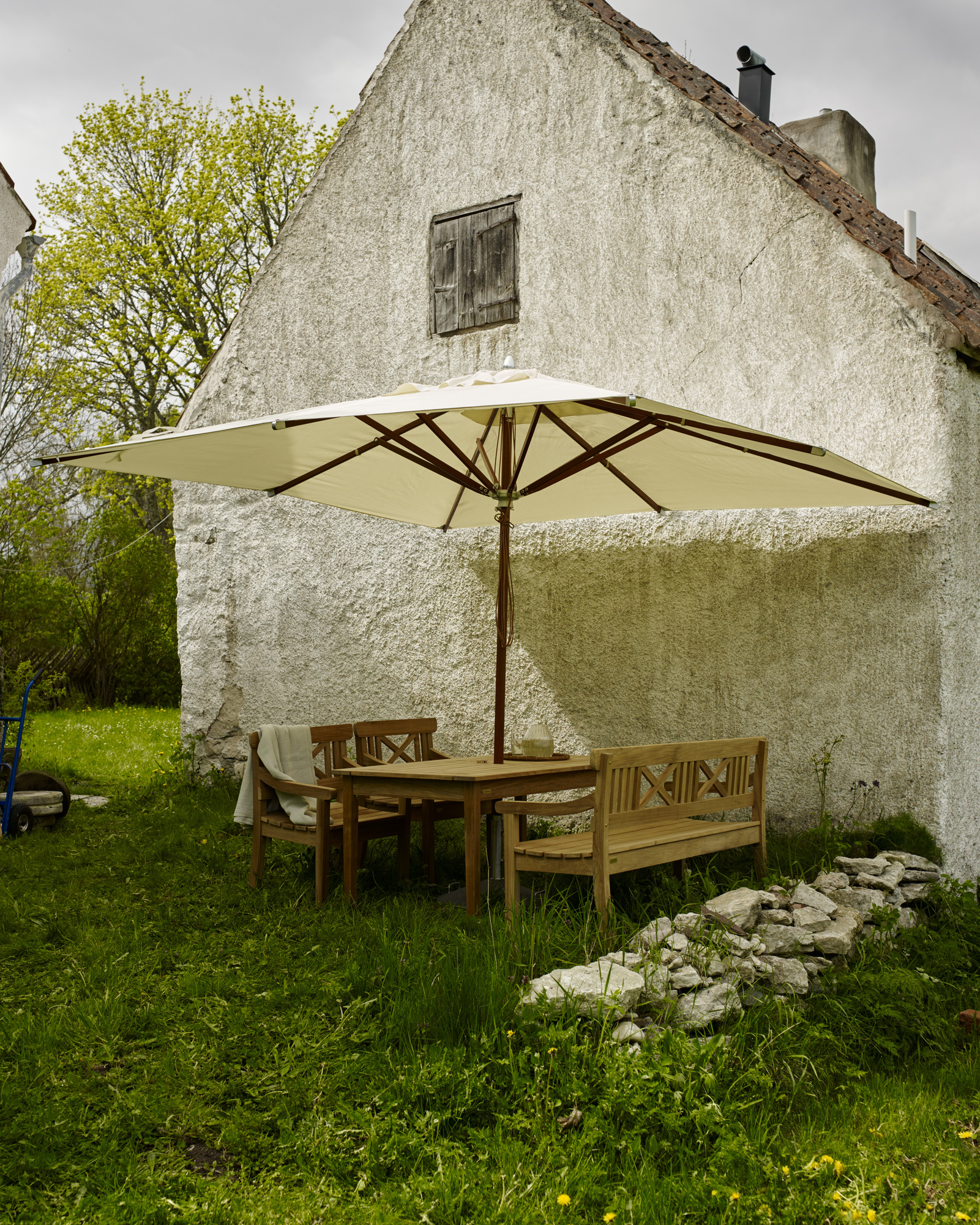 Drachmann Bank von Skagerak by Fritz Hansen im Garten mit Tisch und Sonnenschirm.