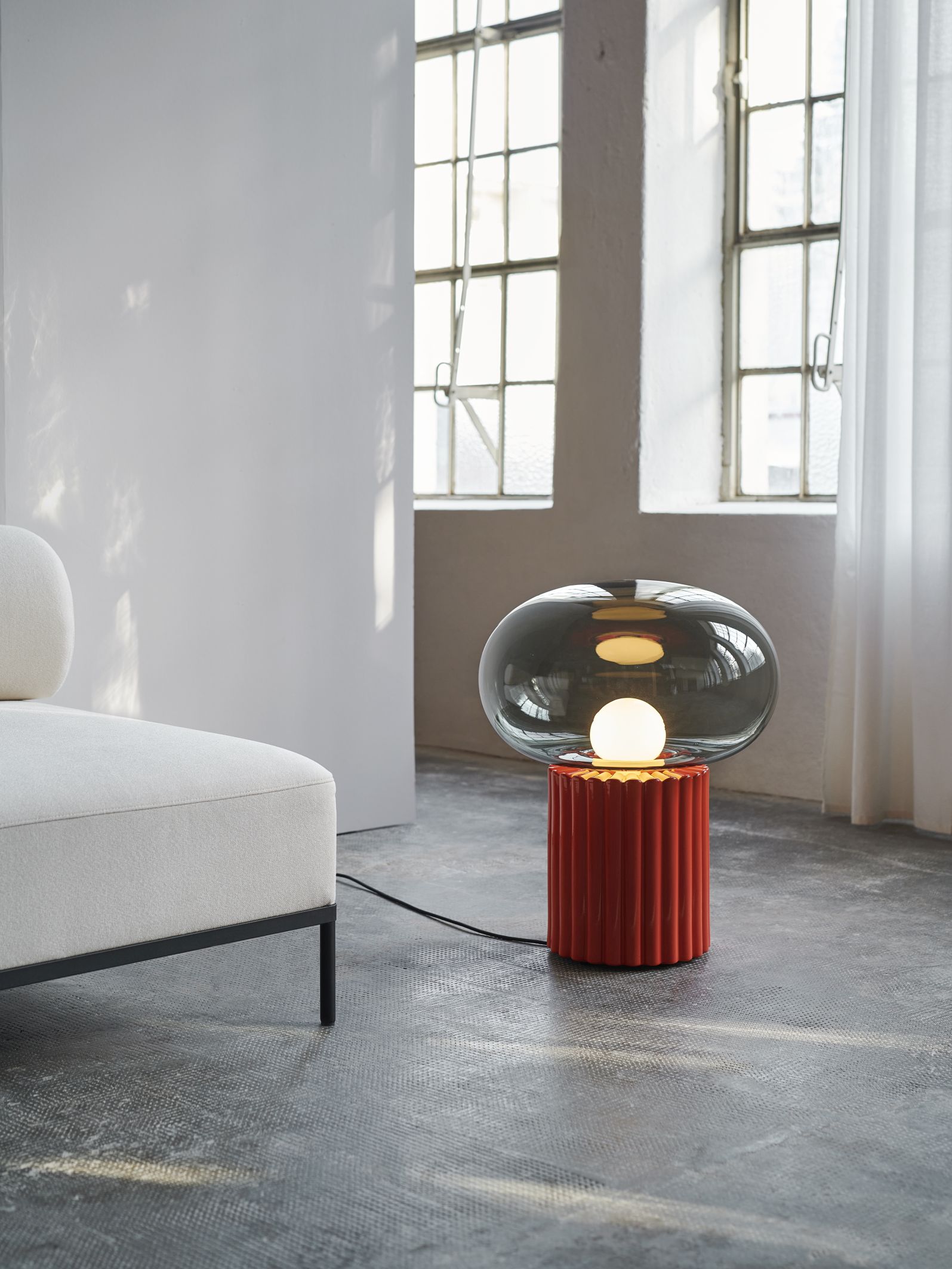 Fungi Bodenleuchte Favius: Moderne Stehlampe mit grauem Glasschirm und geriffeltem, rotem Sockel.