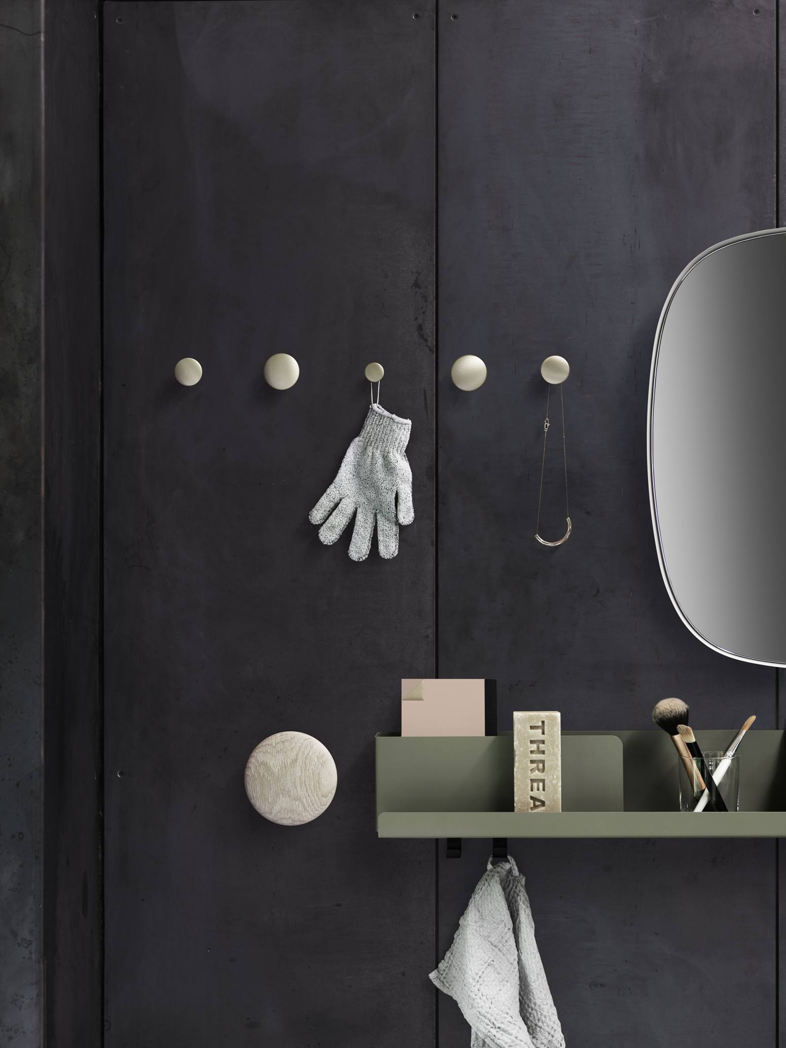 Muuto Folded Shelves Regal in Schwarz, 51x22 cm, an dunkler Wand mit Accessoires und Spiegel.