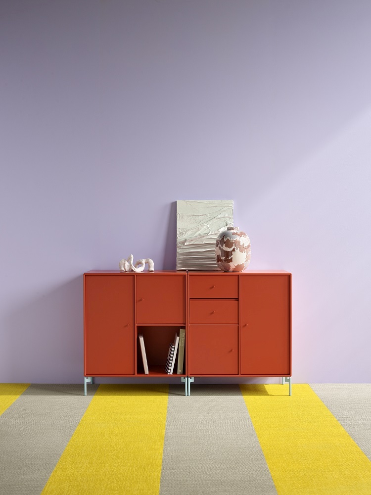 Orangefarbenes Sideboard von Montana mit Türen und Schubladen vor lila Wand und gelb-grauem Teppich.