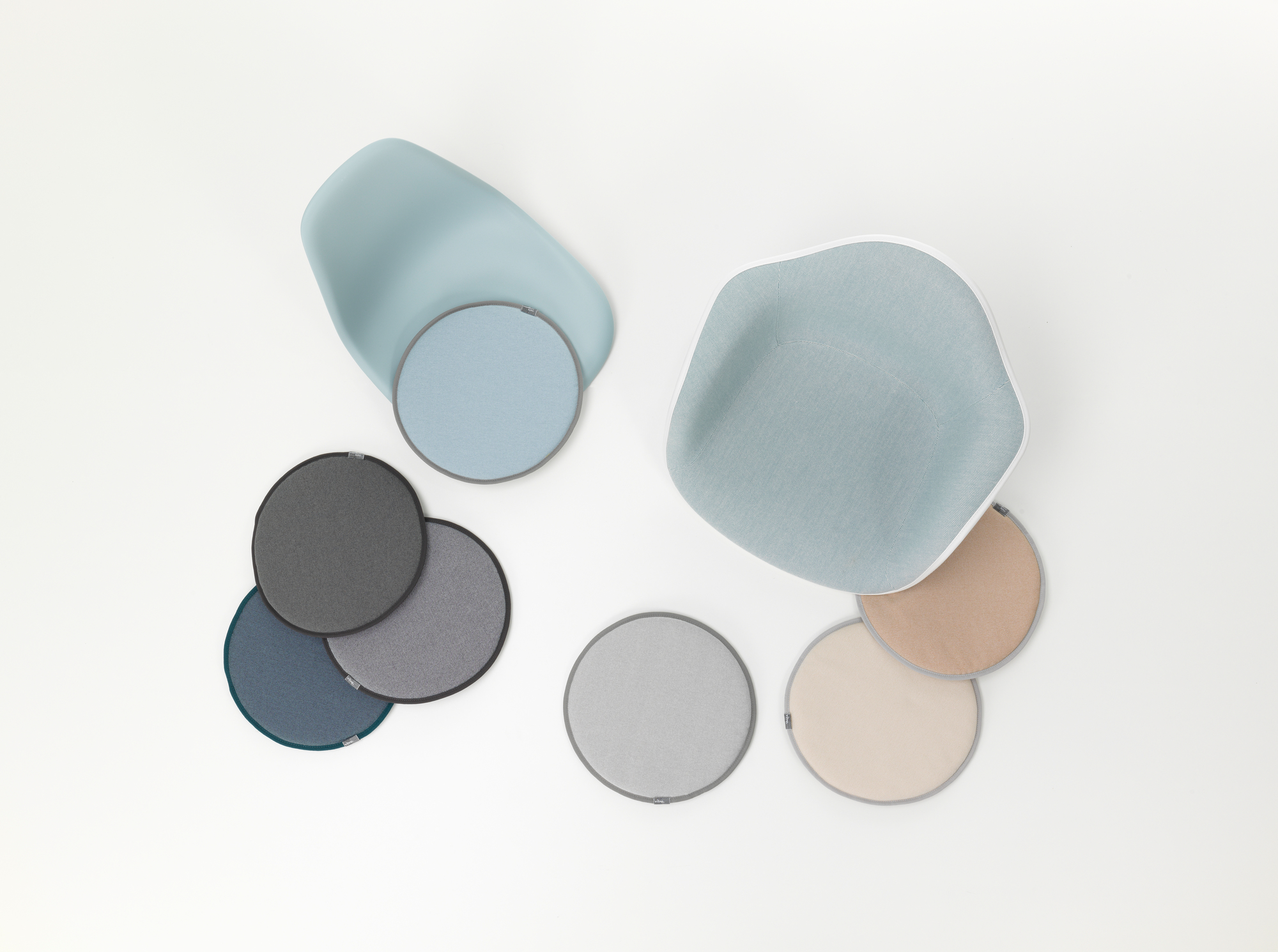 Vitra Seat Dot Sitzkissen in Grün- und Cognactönen, runde Form, Textur und Stühle im Hintergrund.