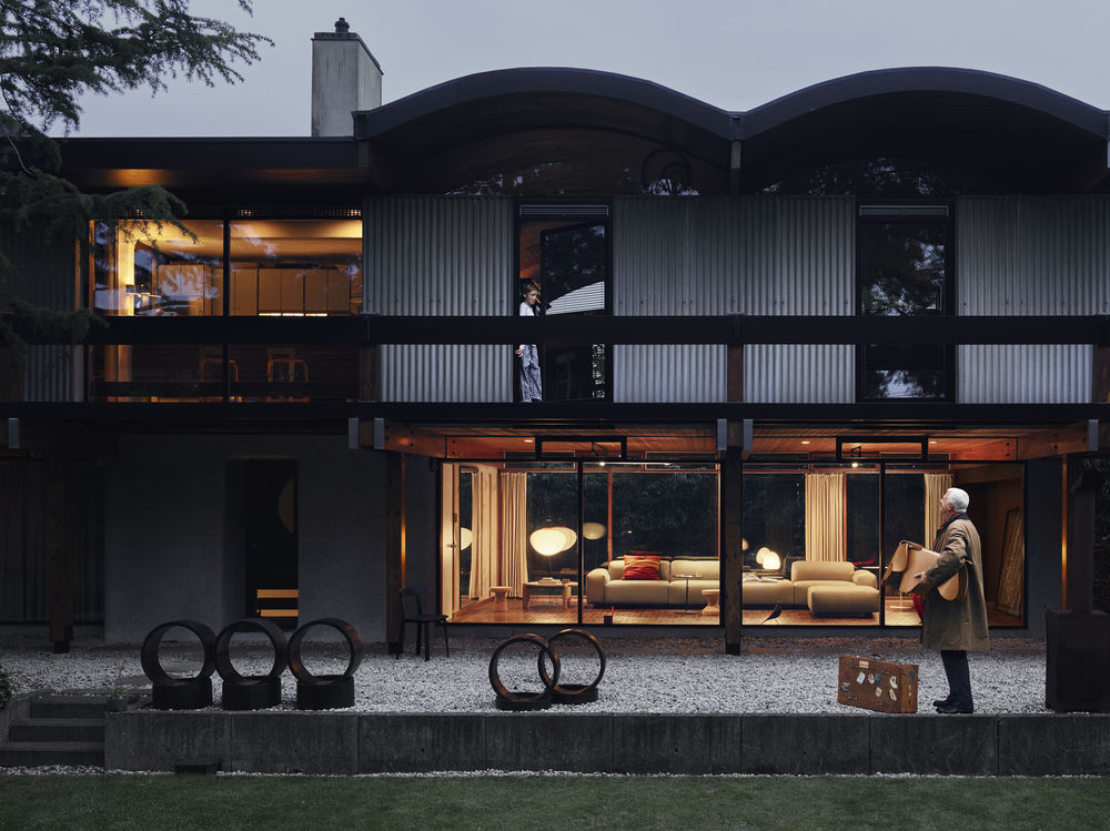 Außenansicht eines modernen Hauses mit Designermöbeln und Dekoration, Mann mit Koffer im Garten.