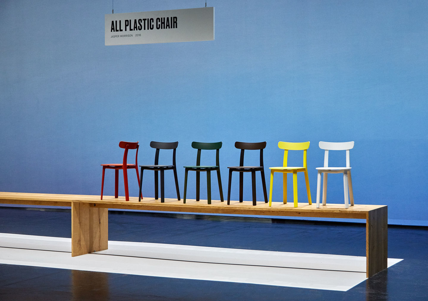 Vitra All Plastic Chair Outdoor Stühle in verschiedenen Farben auf einer Holzbank.
