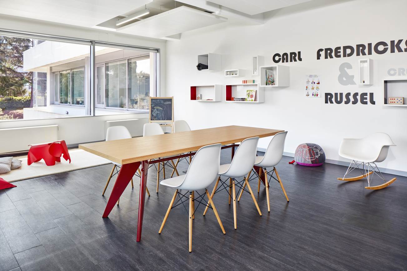 Vitra EM Table Holztisch, 240 cm lang, mit roten Beinen und weißen Stühlen.