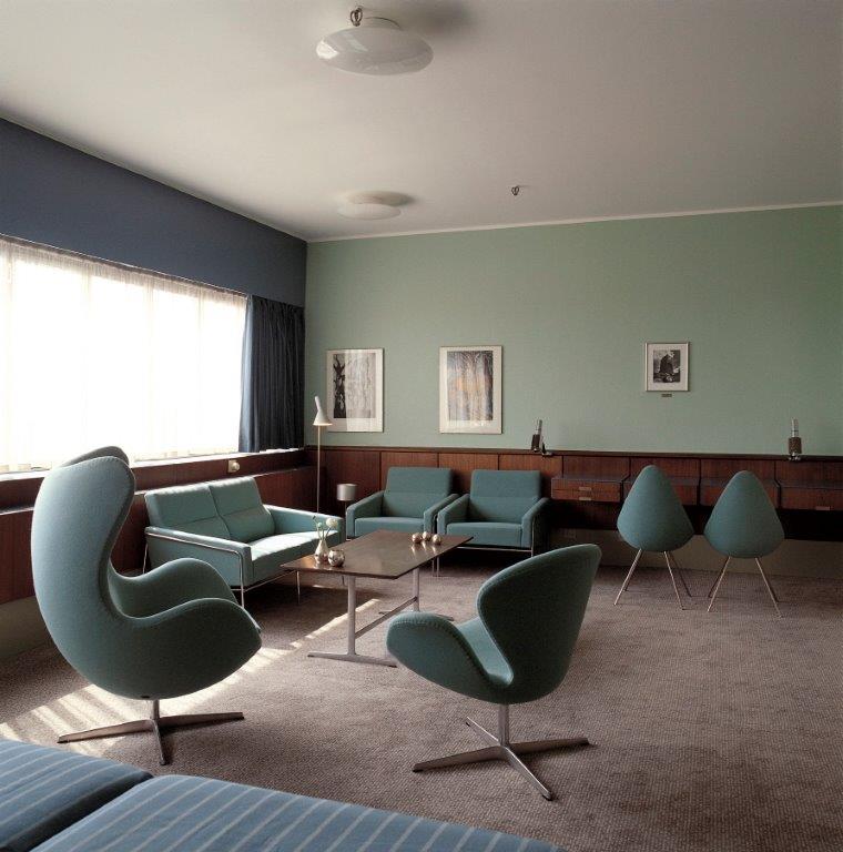 Innenaufnahme mit blaugrünen Egg Chairs und passenden Sofas von Fritz Hansen in einem stilvollen Wohnzimmer.