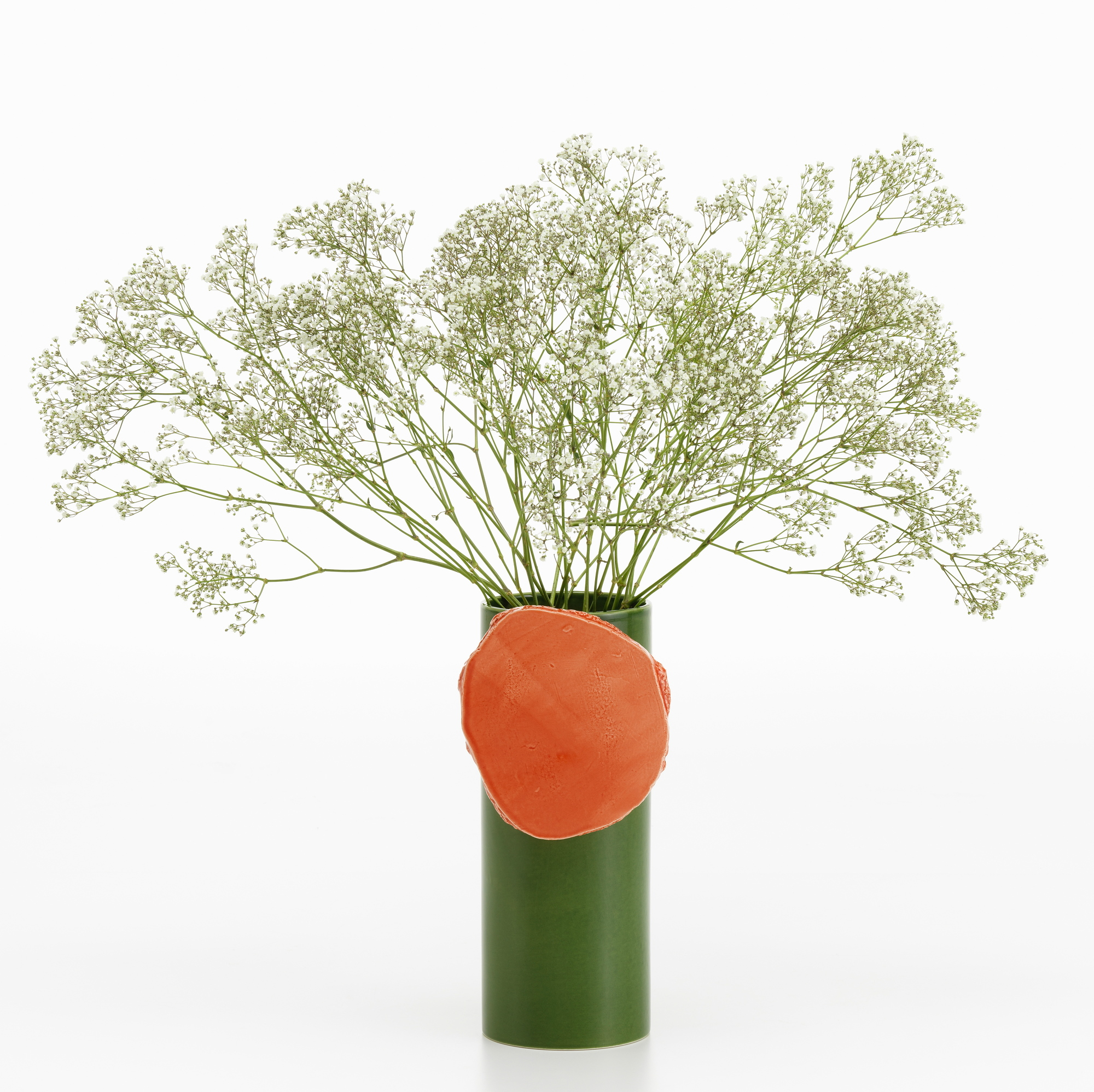 Vitra Découpage Vase: Grüne Design-Vase mit orangem Dekoelement und filigranem Schleierkraut auf weißem Hintergrund.
