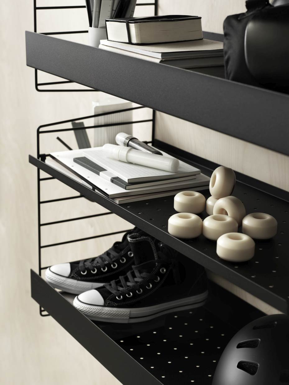 Detailaufnahme des String Furniture Regalsystems mit Schuhen, Skateboard-Rollen und Büroartikeln.