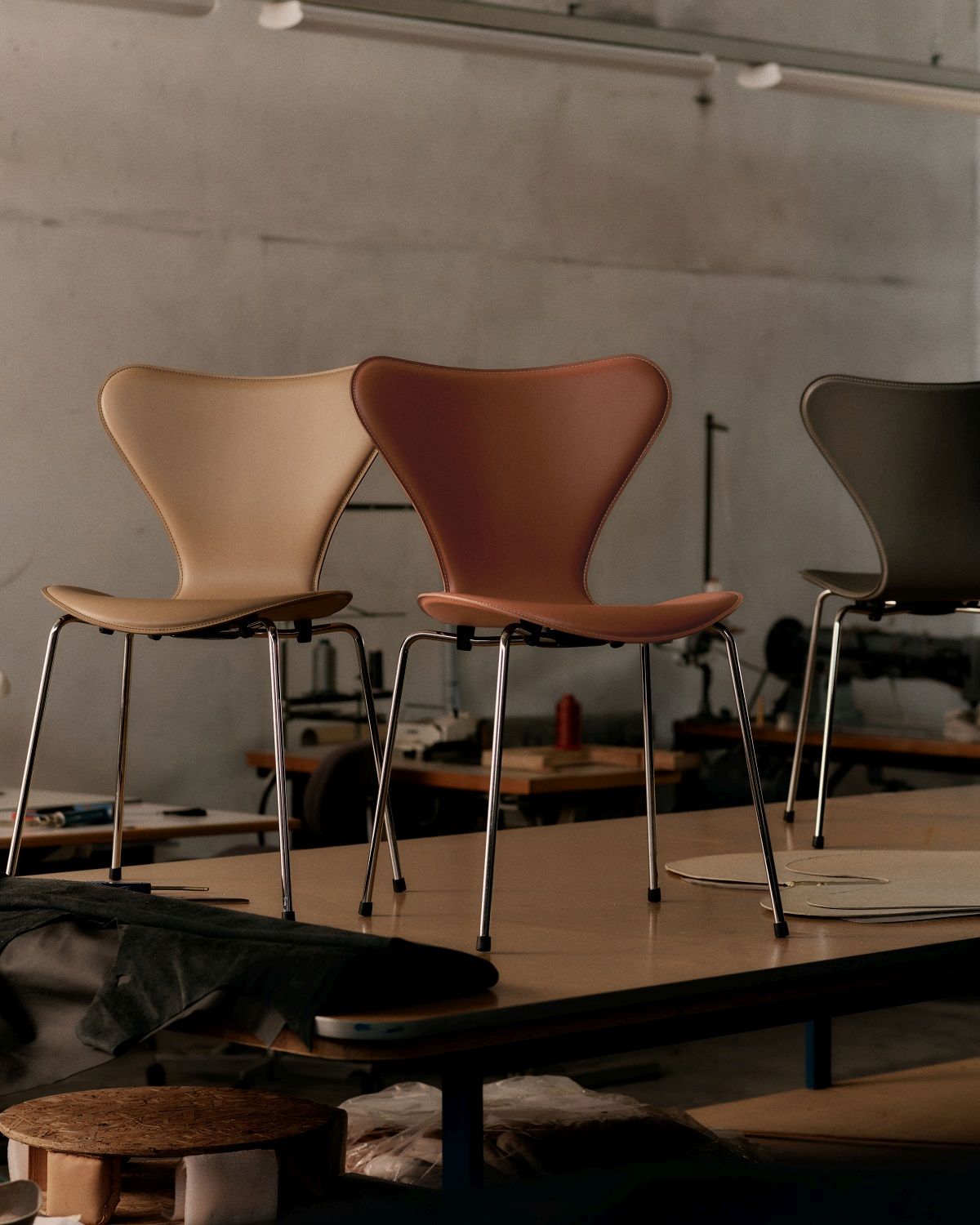 Drei Fritz Hansen Serie 7 Stühle mit Lederbezug in Beige, Braun und Grau im Atelier.