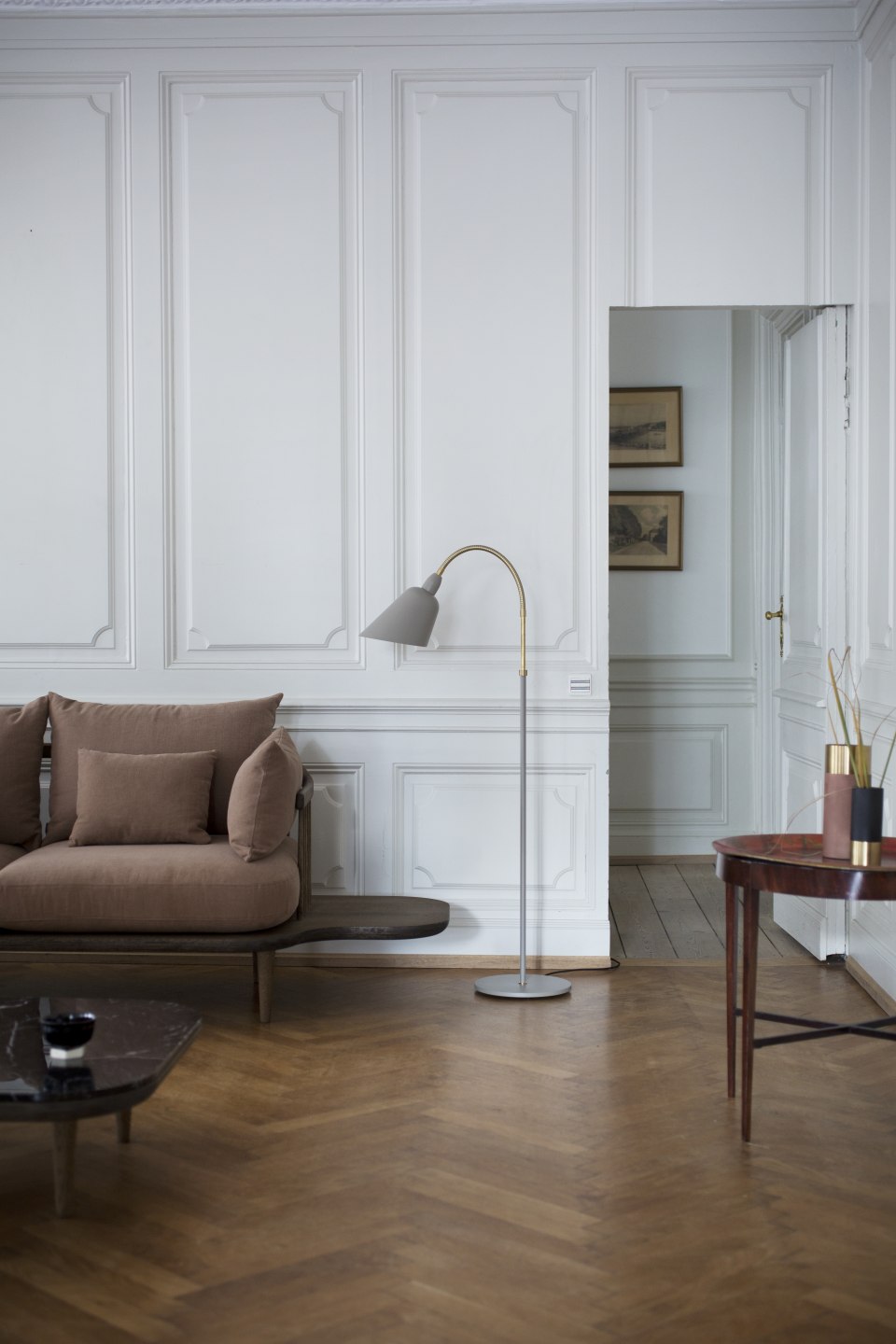 Wohnzimmer mit braunem Sofa, Stehlampe und Fly Table Couchtisch von AndTradition auf Parkettboden.