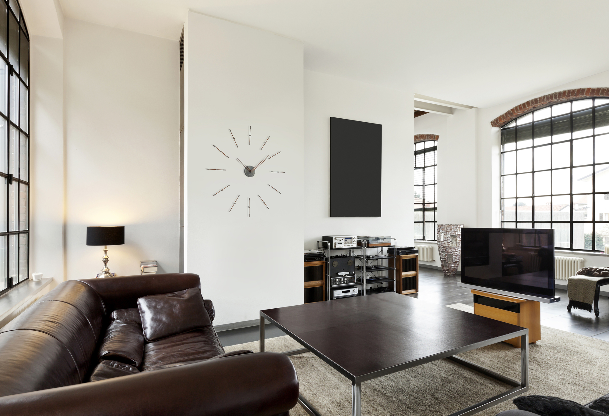 Moderne Mini Merlin Wanduhr von Nomon in einem stilvollen Wohnzimmer. Design Wanddekoration.