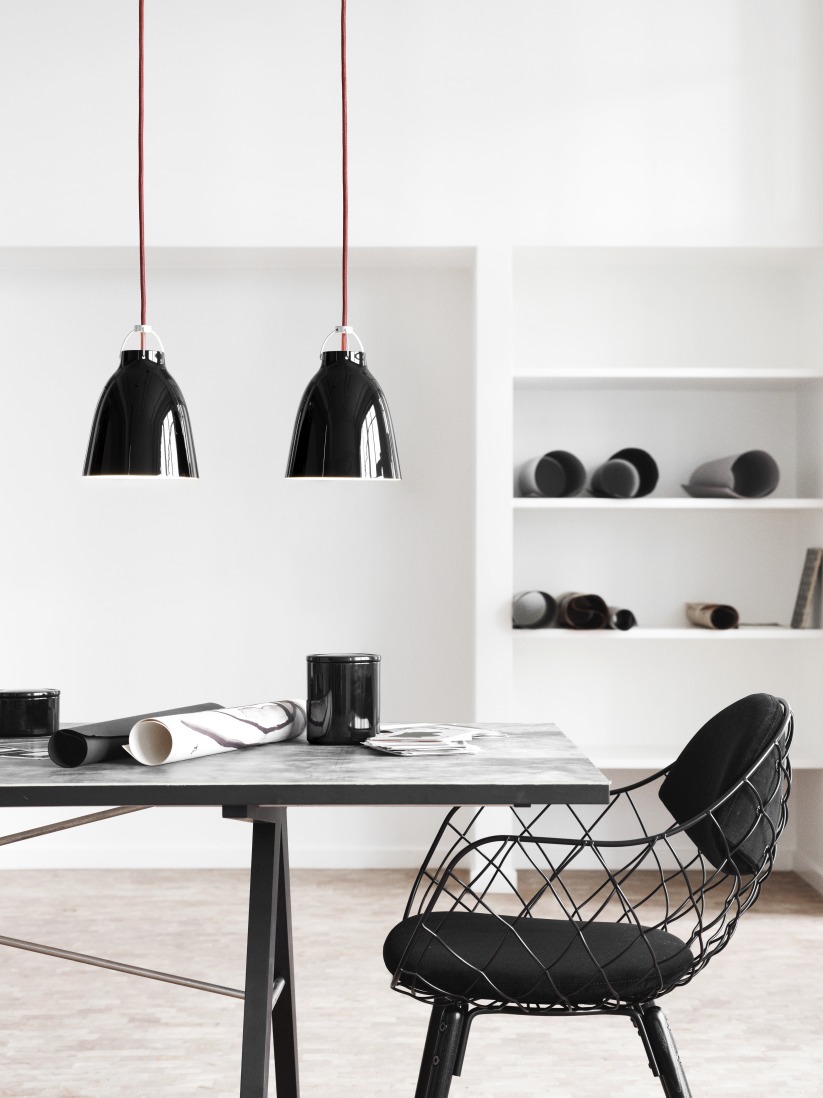 Zwei schwarze Caravaggio Pendelleuchten von Fritz Hansen hängen über einem Esstisch in einem minimalistischen Raum.
