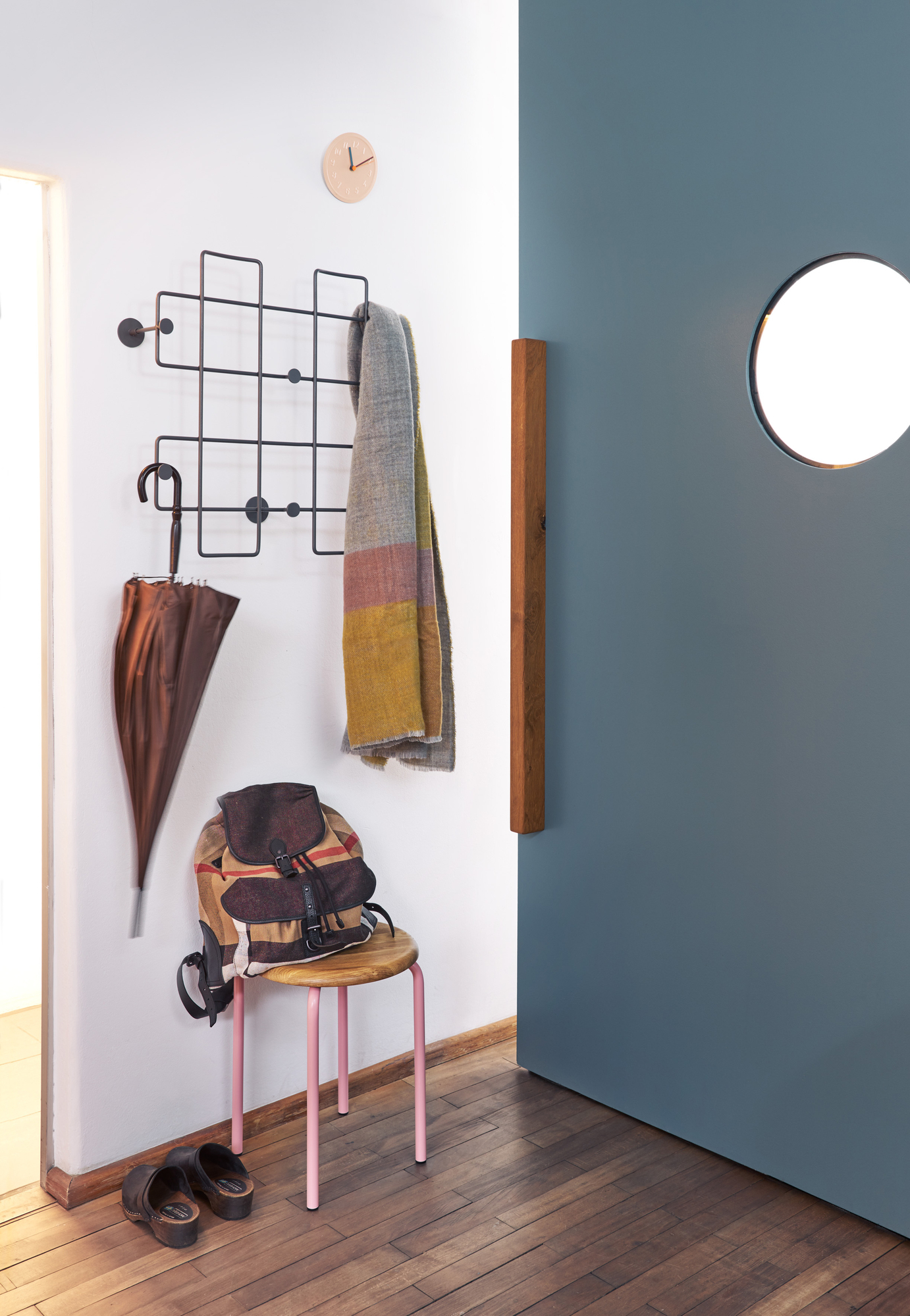 Flur-Interieur mit Richard Lampert Stapelhocker, Garderobe mit Accessoires, Rucksack und Holzschuhen auf Parkettboden.