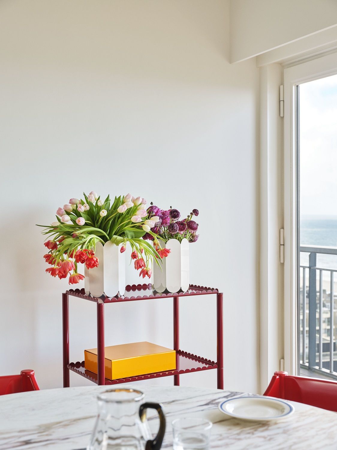 Stahlblauer Arcs Trolley Servierwagen von Hay mit Blumenvasen und gelber Box im modernen Interieur.
