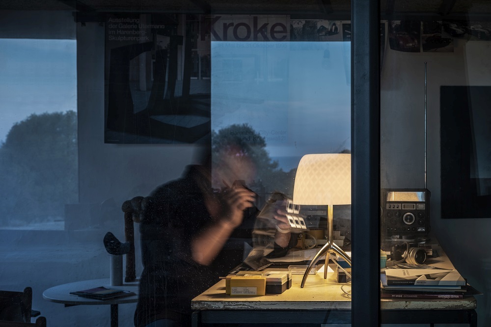 Nahaufnahme der Lumiere Tischleuchte von Foscarini auf einem Schreibtisch mit Vintage-Radio und Büchern.