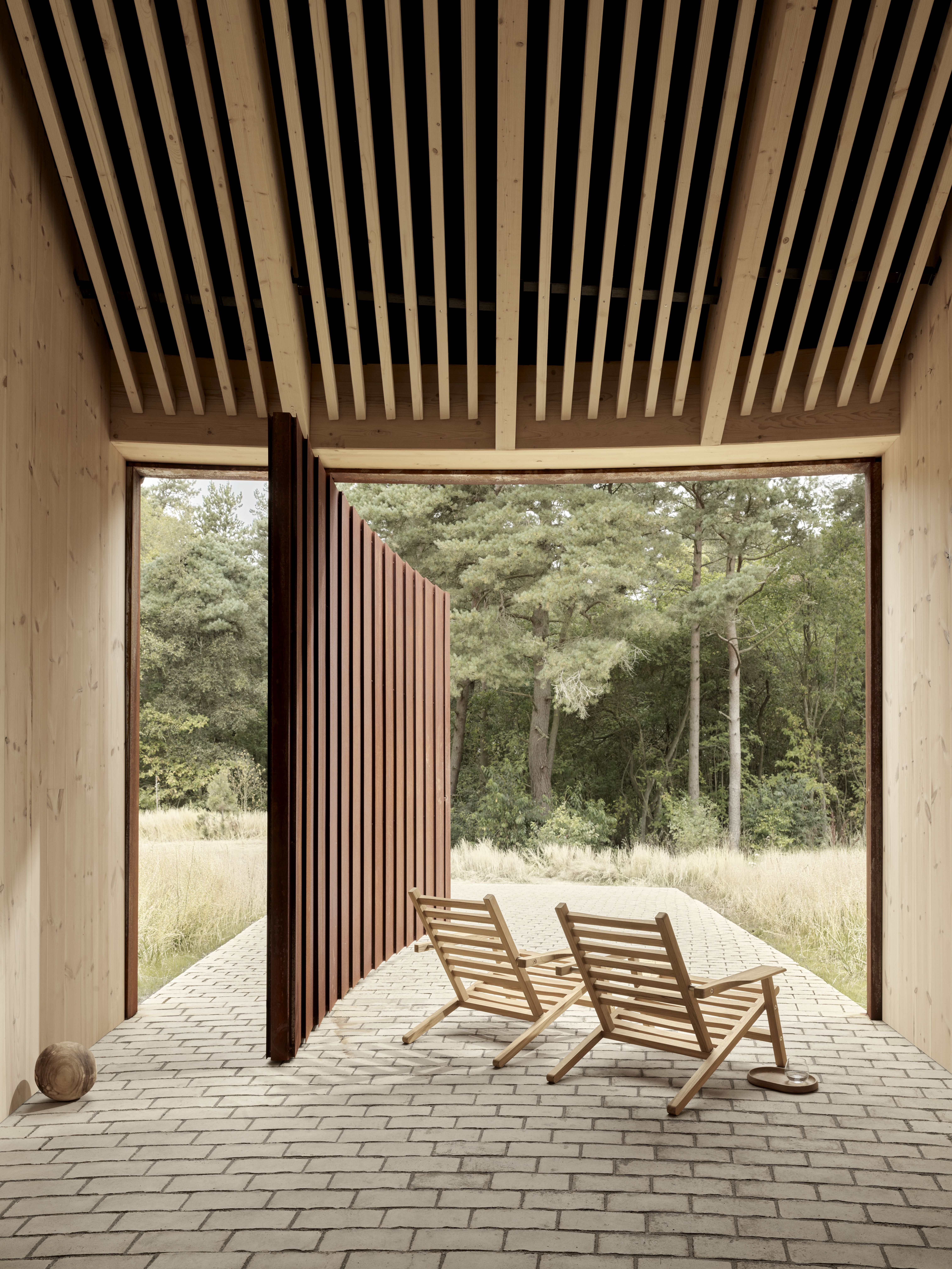Zwei AH603 Teak Carl Hansen Sonnenstühle auf einer Terrasse mit Blick in die Natur.