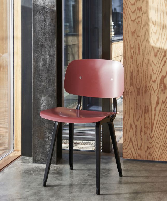 Roter Revolt Chair Stuhl von Hay mit schwarzem Gestell vor modernem Hintergrund.