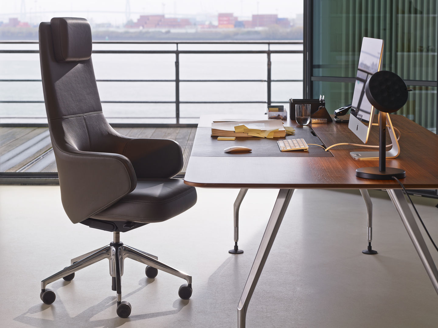 Grand Executive Highback Konferenzstuhl von Vitra in braunem Leder vor modernem Schreibtisch.