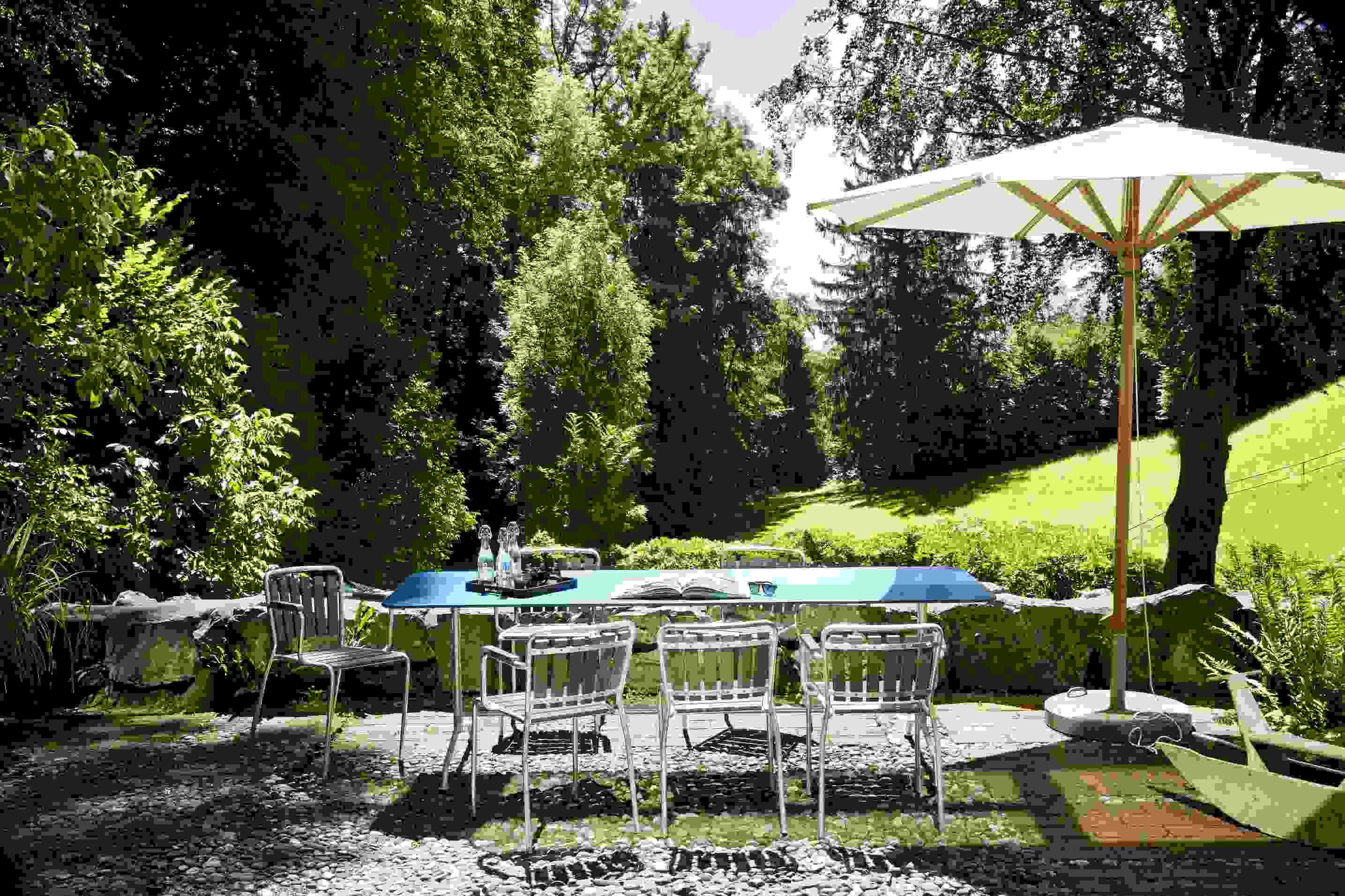 Haefeli Esstisch Outdoor mit Stühlen und Sonnenschirm im Garten, Tischplatte in Embru Gelb RAL 1023.