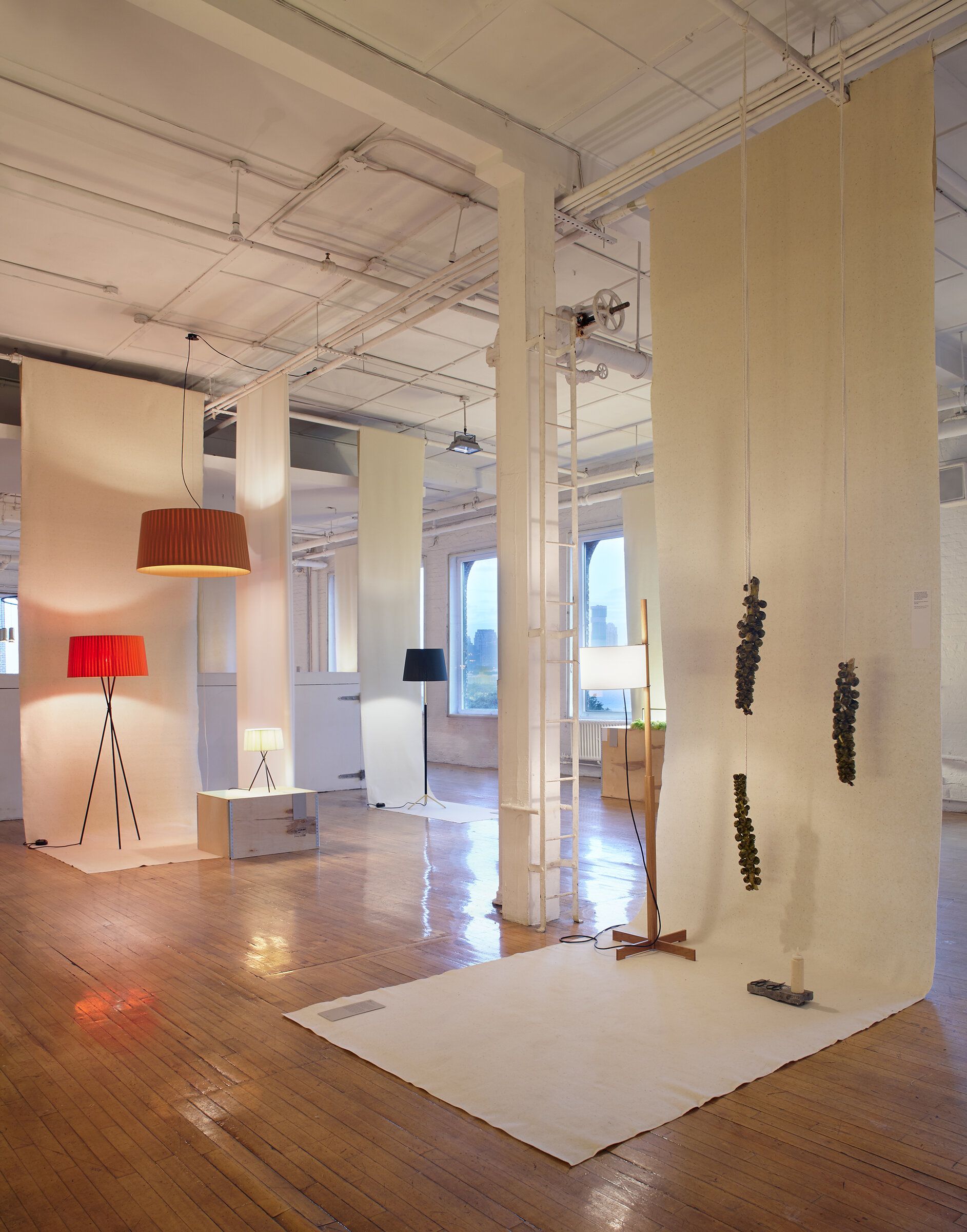 Ausstellung mit verschiedenen Lampen, darunter eine rote Tripode Stehleuchte von Santa & Cole.