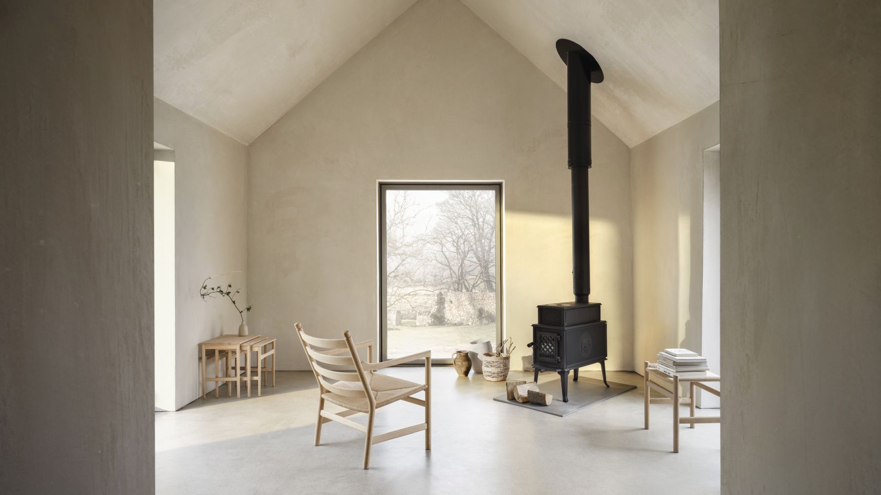 Helles Wohnzimmer mit Carl Hansen & Søn CH004 Nesting Tables Beistelltischen aus Holz und Kaminofen.