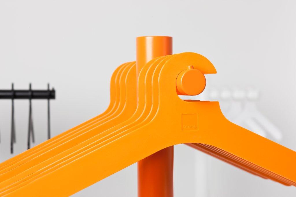 Orangefarbene Cascando Kleiderbügel am Ständer, moderne Garderobenlösung für Büro und Zuhause.