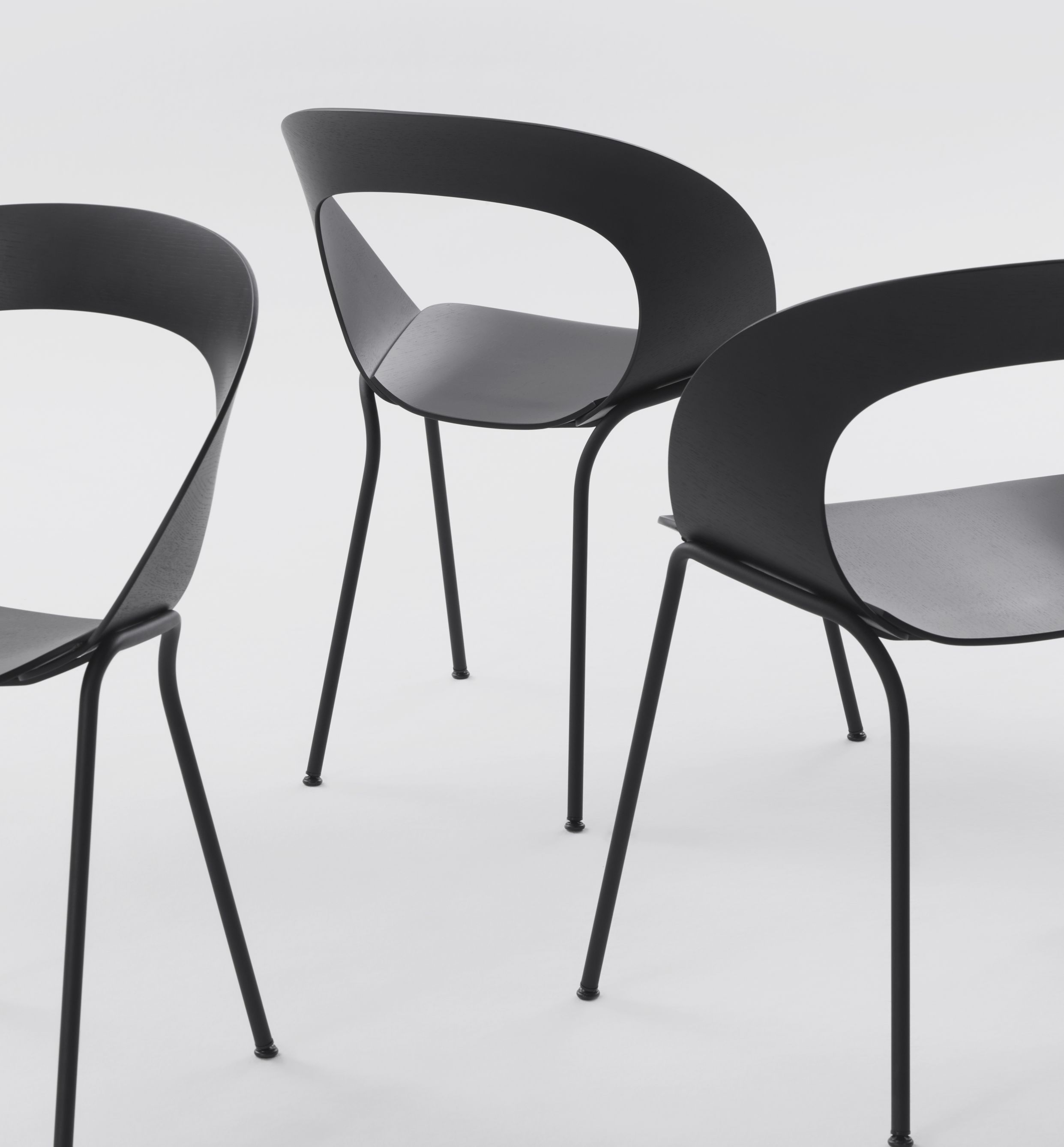 Drei schwarze Mudra Stühle von Brunner mit minimalistischem Design und filigranen Stahlbeinen auf weißem Hintergrund.
