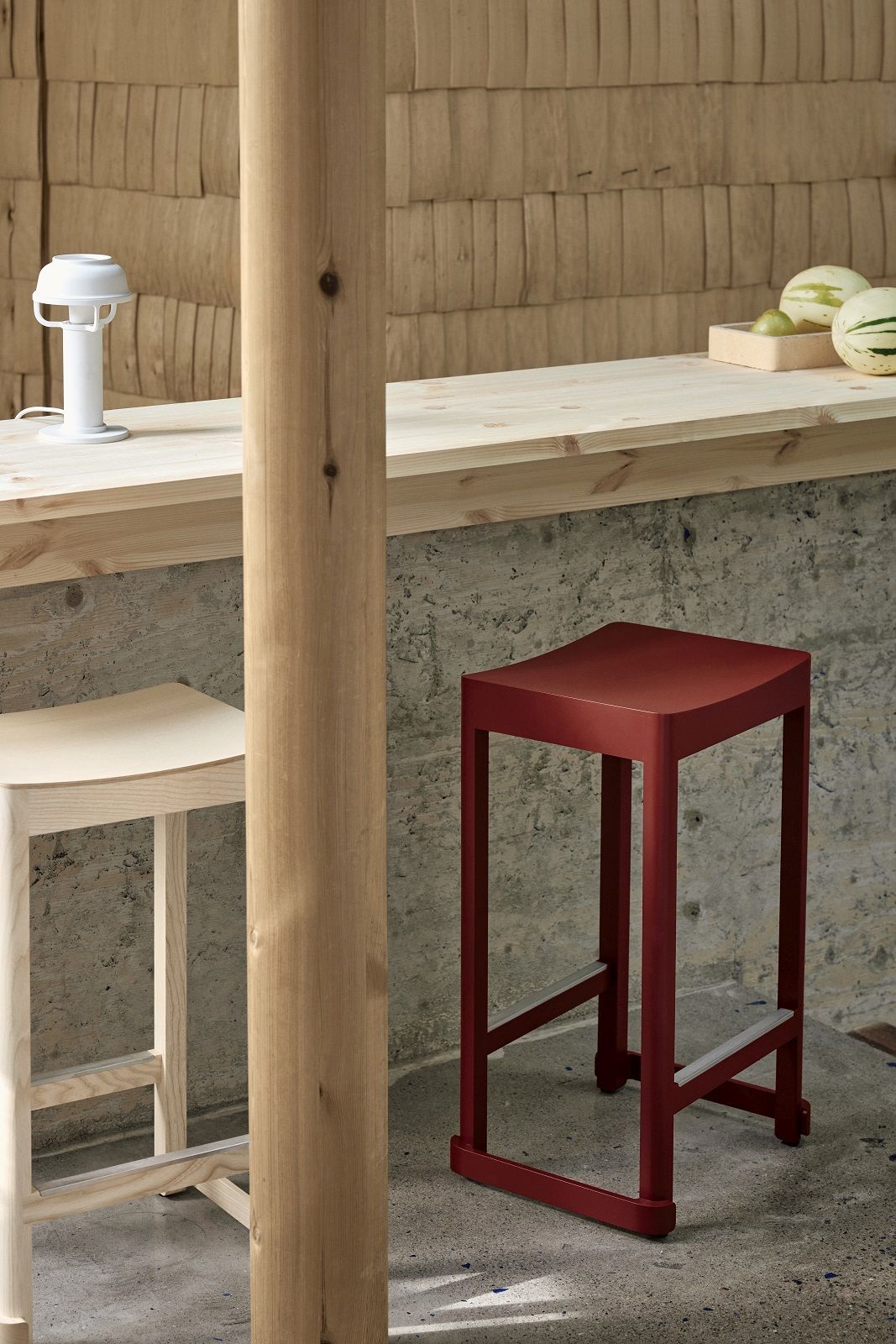 Atelier Bar Stool von Artek: Roter und heller Holz-Barhocker an einer Bartheke.