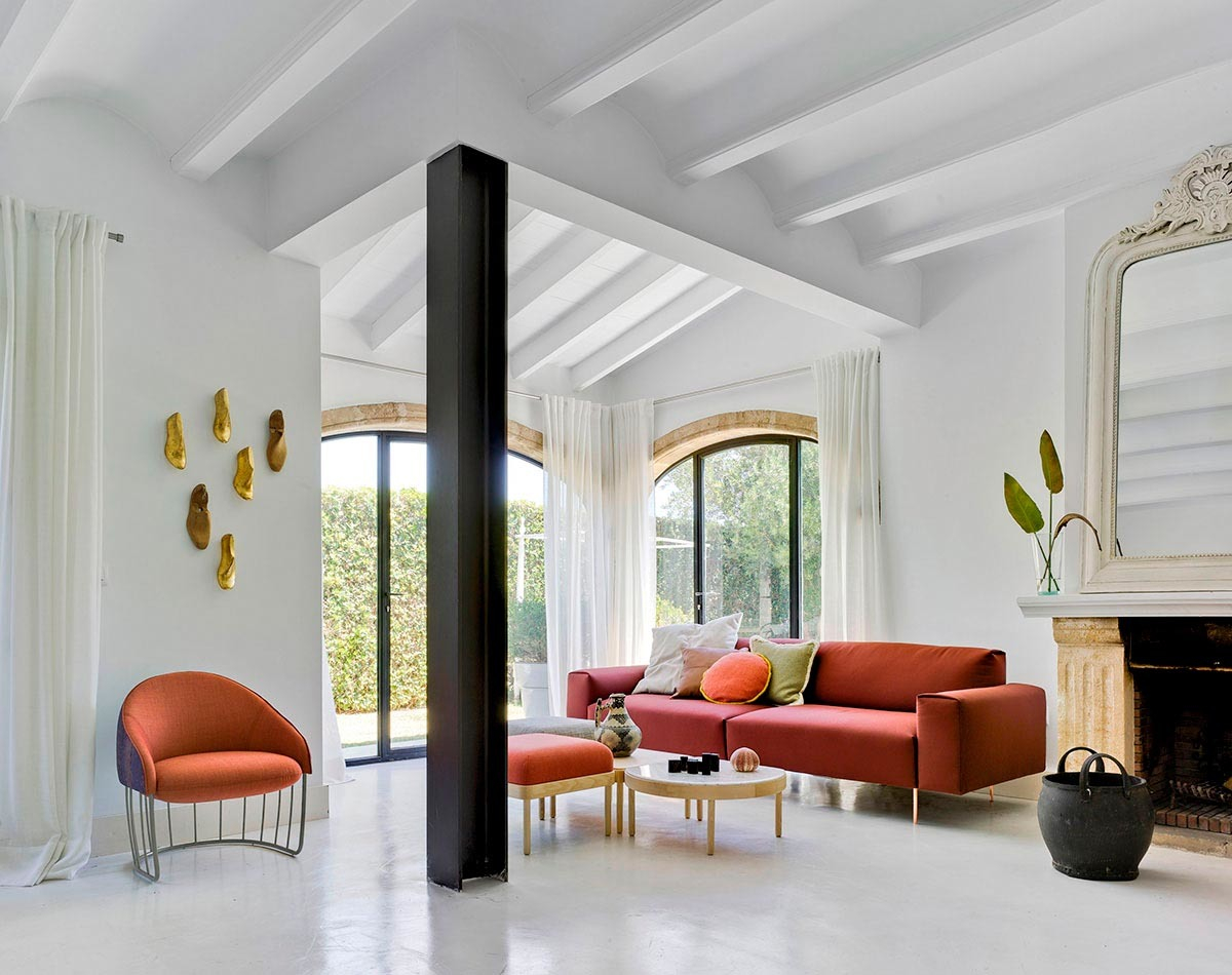 Helles Wohnzimmer mit rotem Tip Toe Sofa von Sancal, Sessel, Couchtisch und Dekoration.