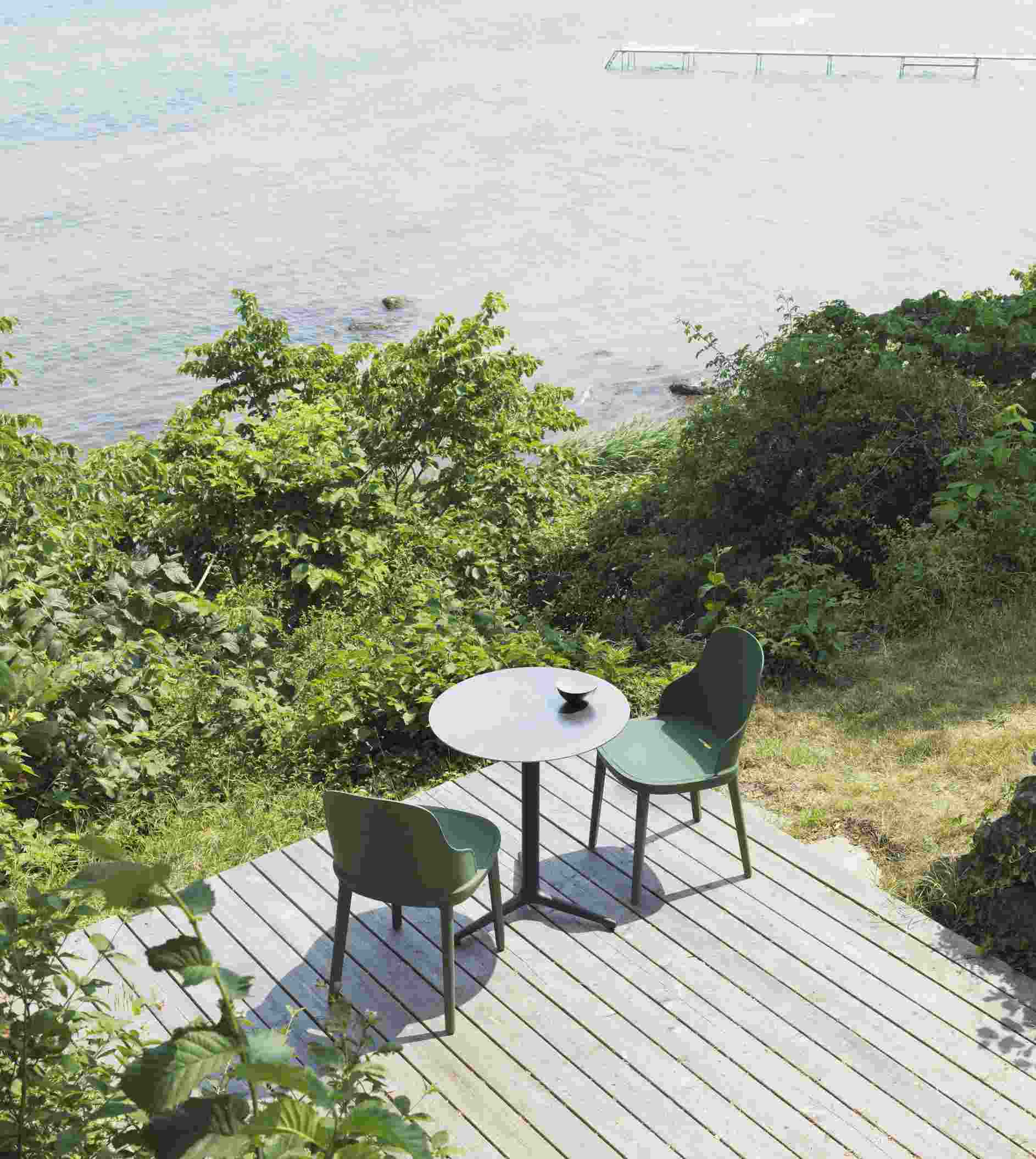 Zwei grüne Allez Stühle von Normann Copenhagen mit kleinem Tisch auf Holzterrasse am Meer.