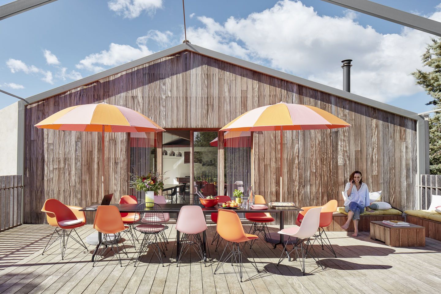 Eames Fiberglass Chair DSR Stühle von Vitra in verschiedenen Farben um einen Esstisch im Freien.