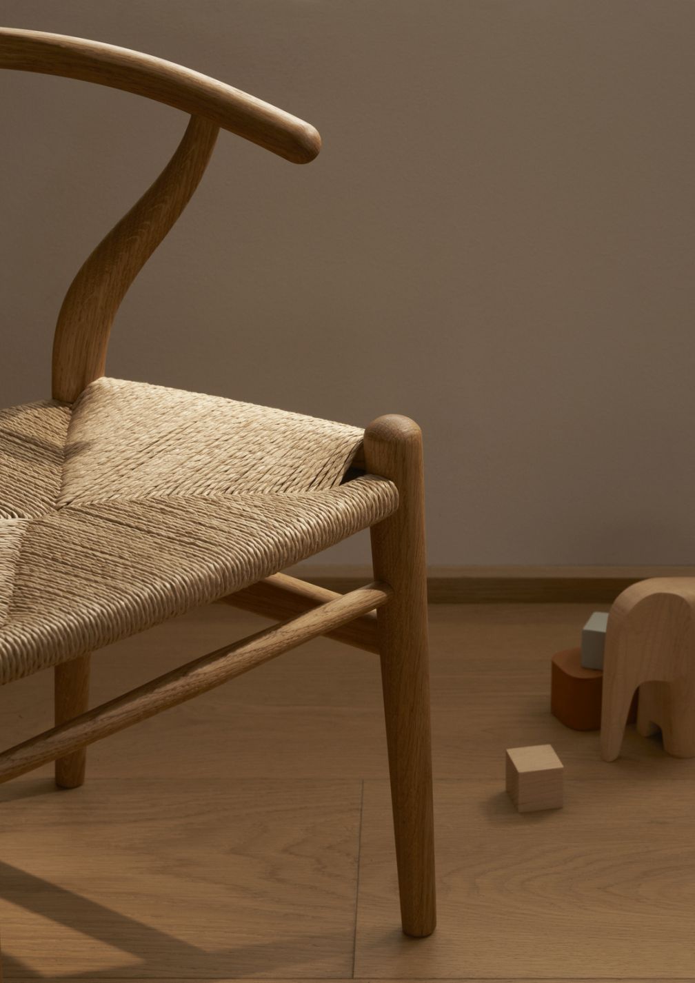 Detailaufnahme des CH24 Wishbone Kinderstuhls von Carl Hansen & Søn mit Holzspielzeug auf Holzboden.