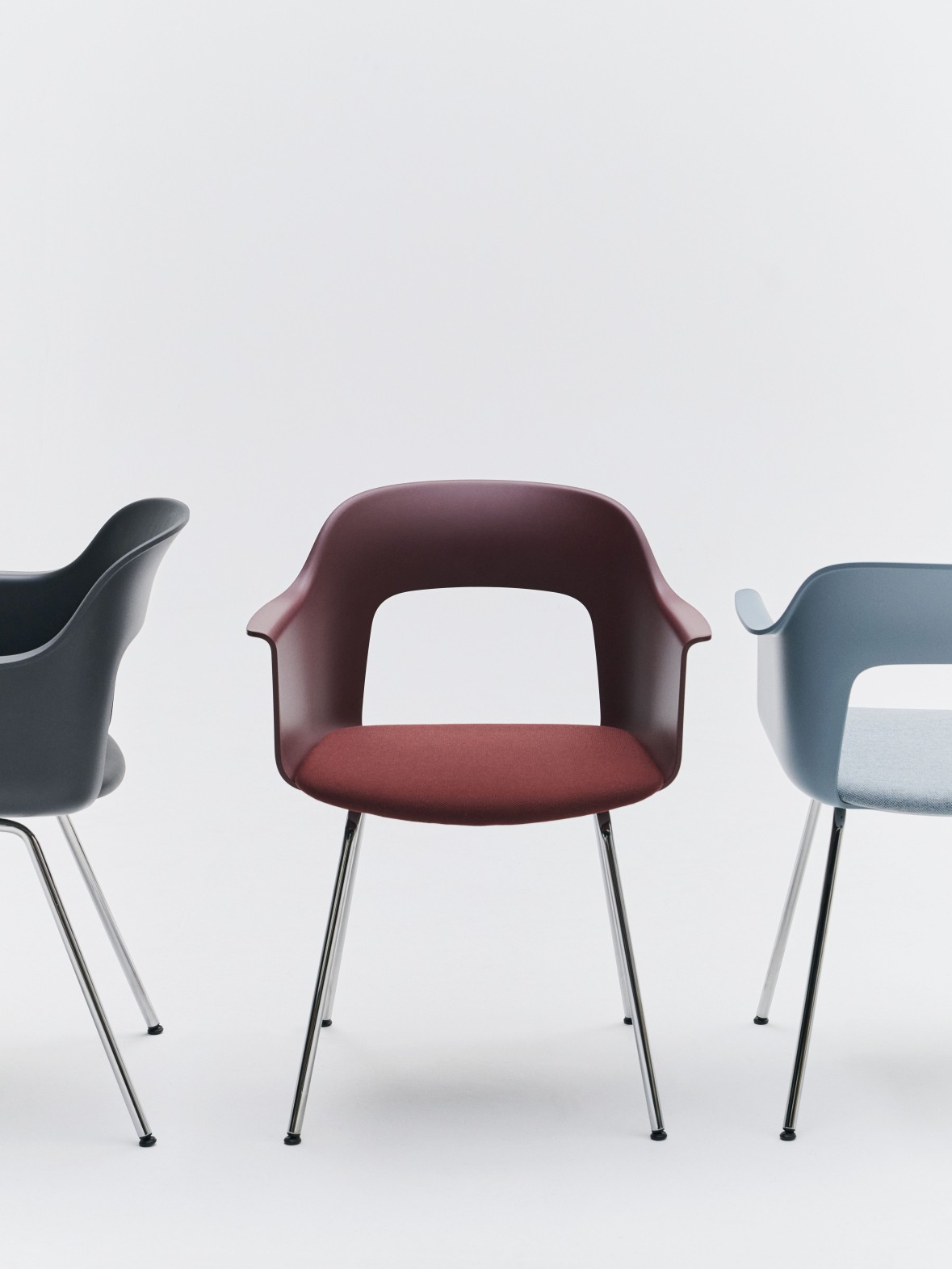 Layout Armchair von Hay: Drei Armlehnstühle in Grau, Rot und Blau mit verchromten Beinen vor weißem Hintergrund.
