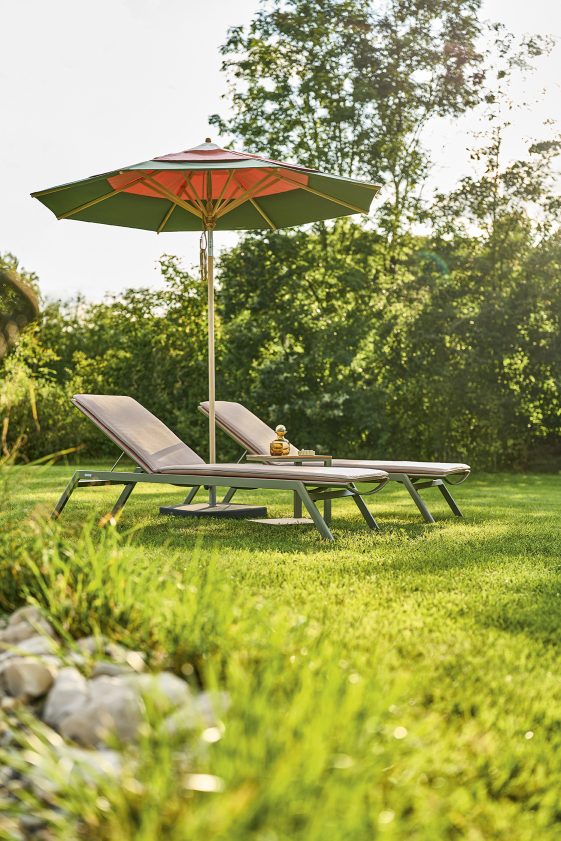 Weishäupl Schirm über zwei Liegestühlen im Garten. Klassischer Sonnenschirm für entspannte Stunden im Freien.