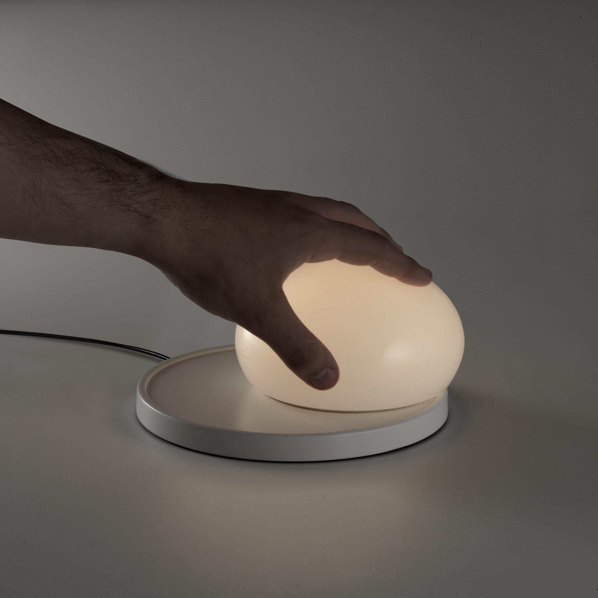 Weiße Bolita Tischleuchte von Marset mit Hand, die das Licht berührt. LED Lampe für Nachttisch.