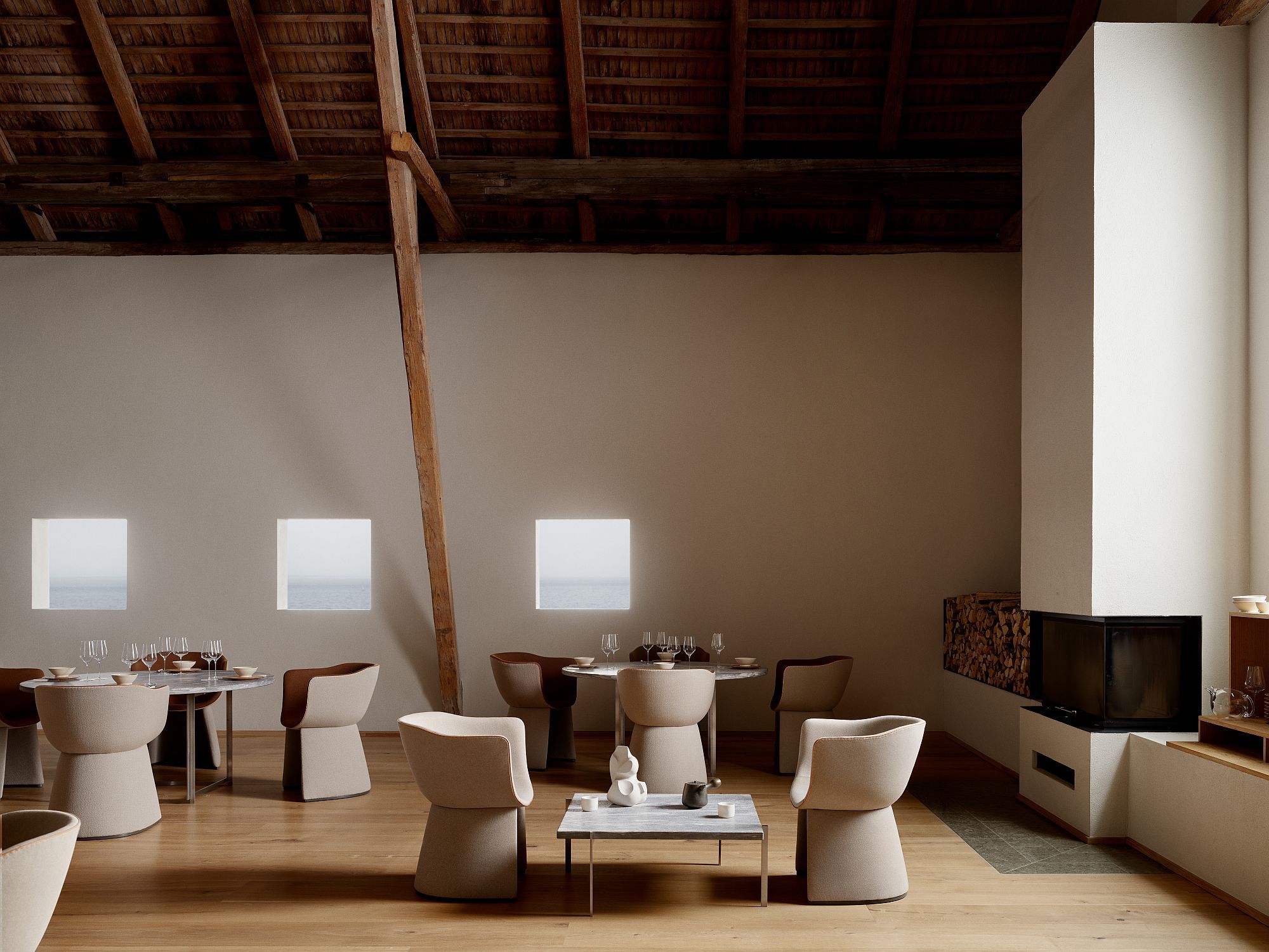 Innenaufnahme mit mehreren Fritz Hansen Monolit Esszimmerstühlen in beigem Stoffbezug um Esstische und Couchtisch gruppiert.