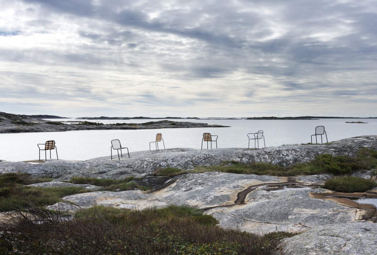 Mehrere Vig Chair Wood Stühle von Normann Copenhagen auf Felsen am Meer, Outdoor-Möbel.