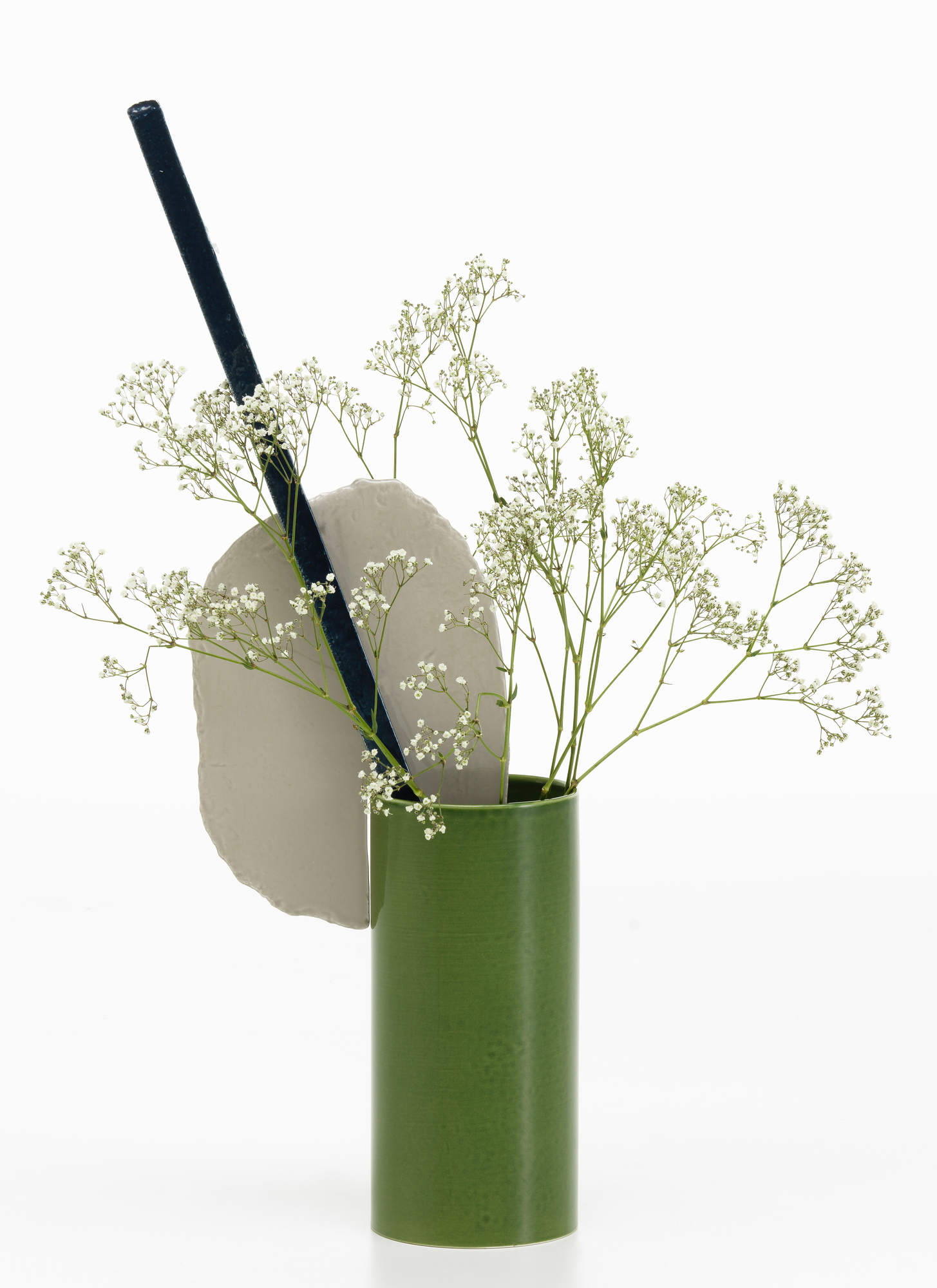 Vitra Découpage Vase: Grüne Design-Vase mit Trockenblumen, Stein-Element und schwarzem Stab auf weißem Hintergrund.