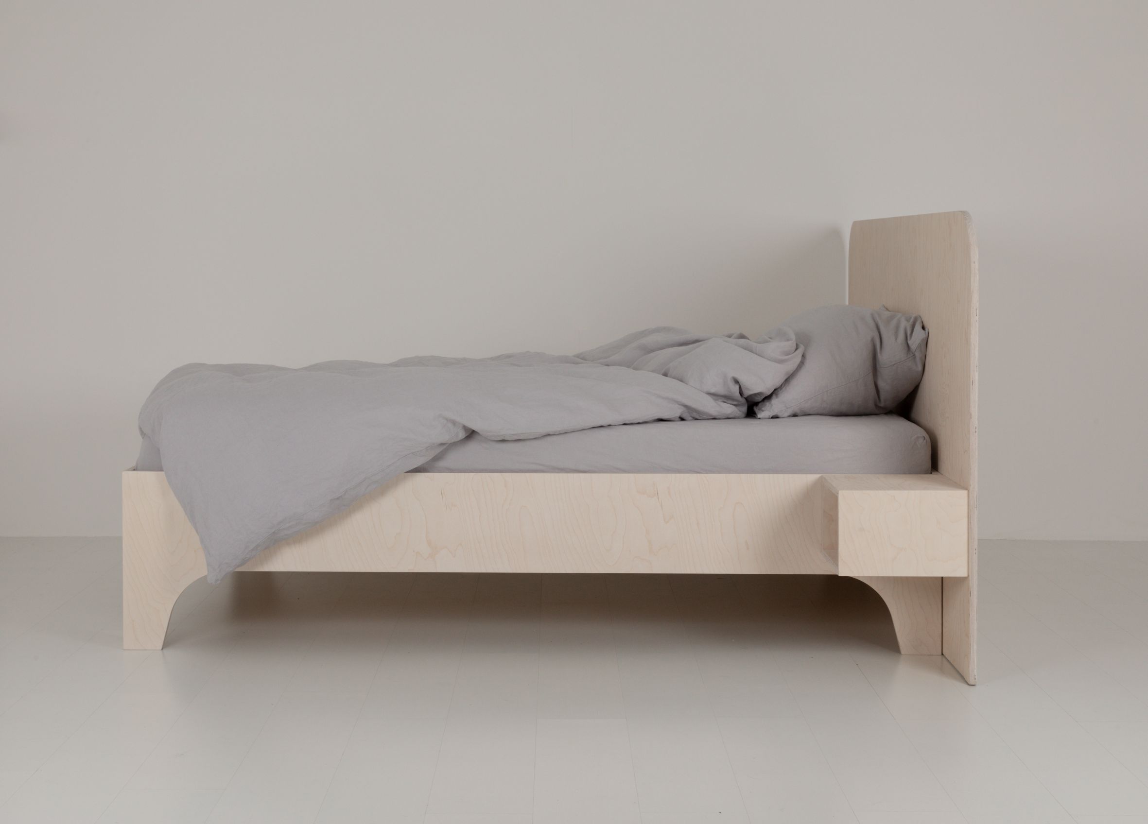 VALENTINA Bett 180x200 cm aus hellem Holz mit grauer Bettwäsche und Nachttischablage.