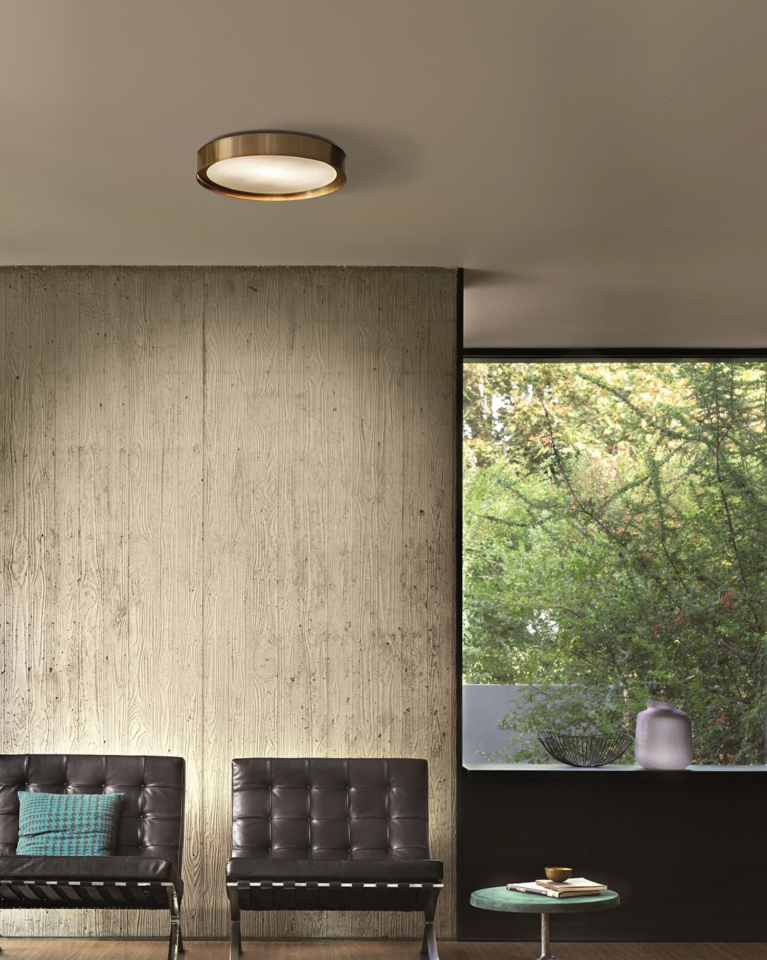 Goldene Berlin Deckenleuchte von Oluce im modernen Wohnzimmer mit Betonwand und Fenster.