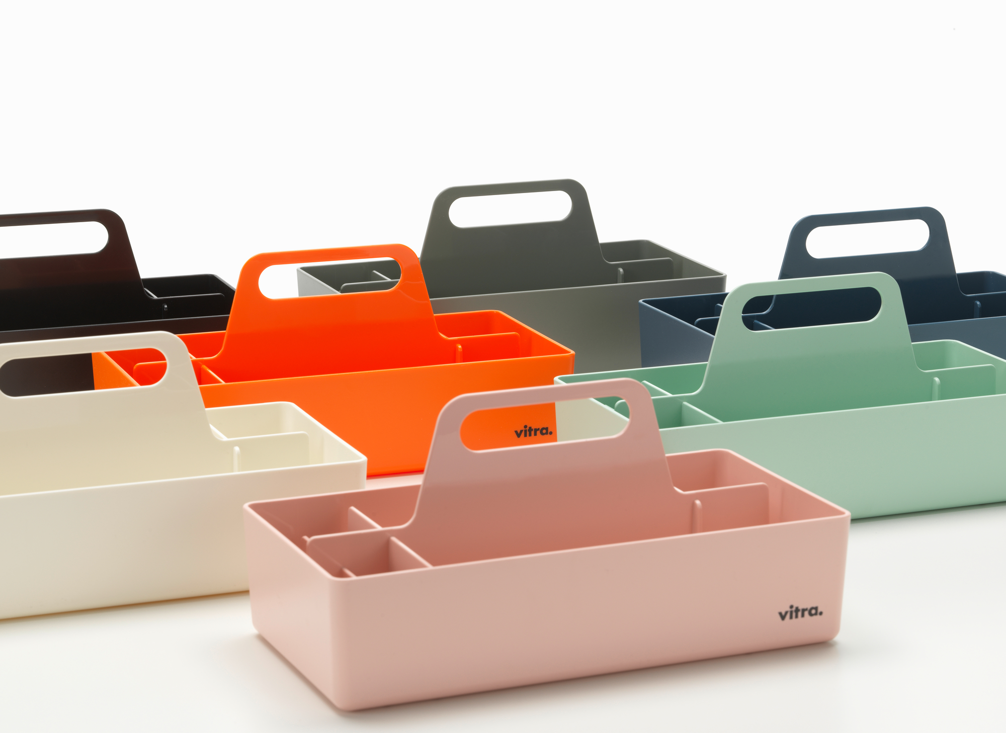 Mehrere Vitra Toolbox Organisationsboxen in verschiedenen Farben, darunter eine weiße, für Bürobedarf und Werkzeug.