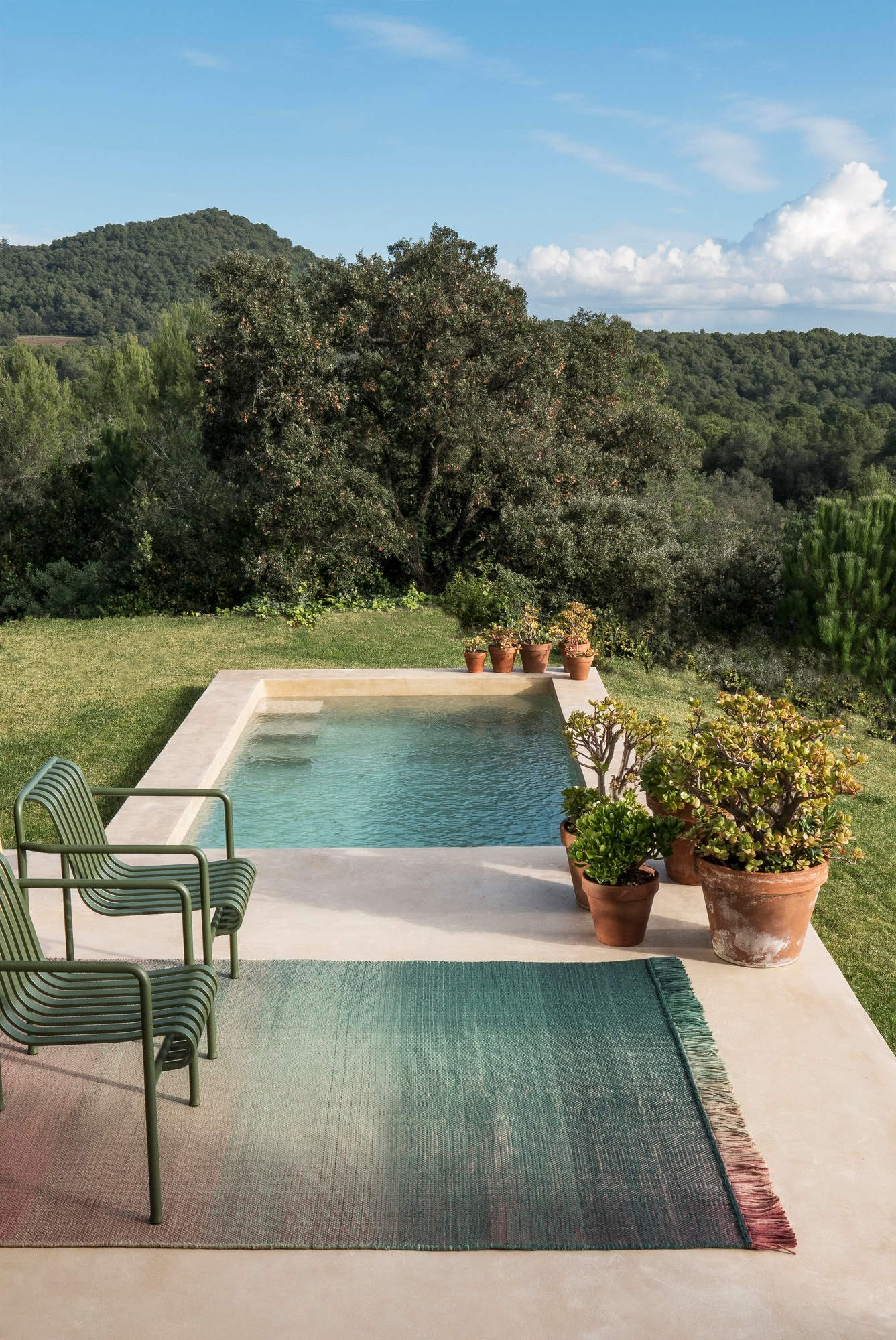 Nanimarquina Shade Outdoor Teppich neben Pool und Gartenmöbeln. Farbverlauf von Grün zu Rot.