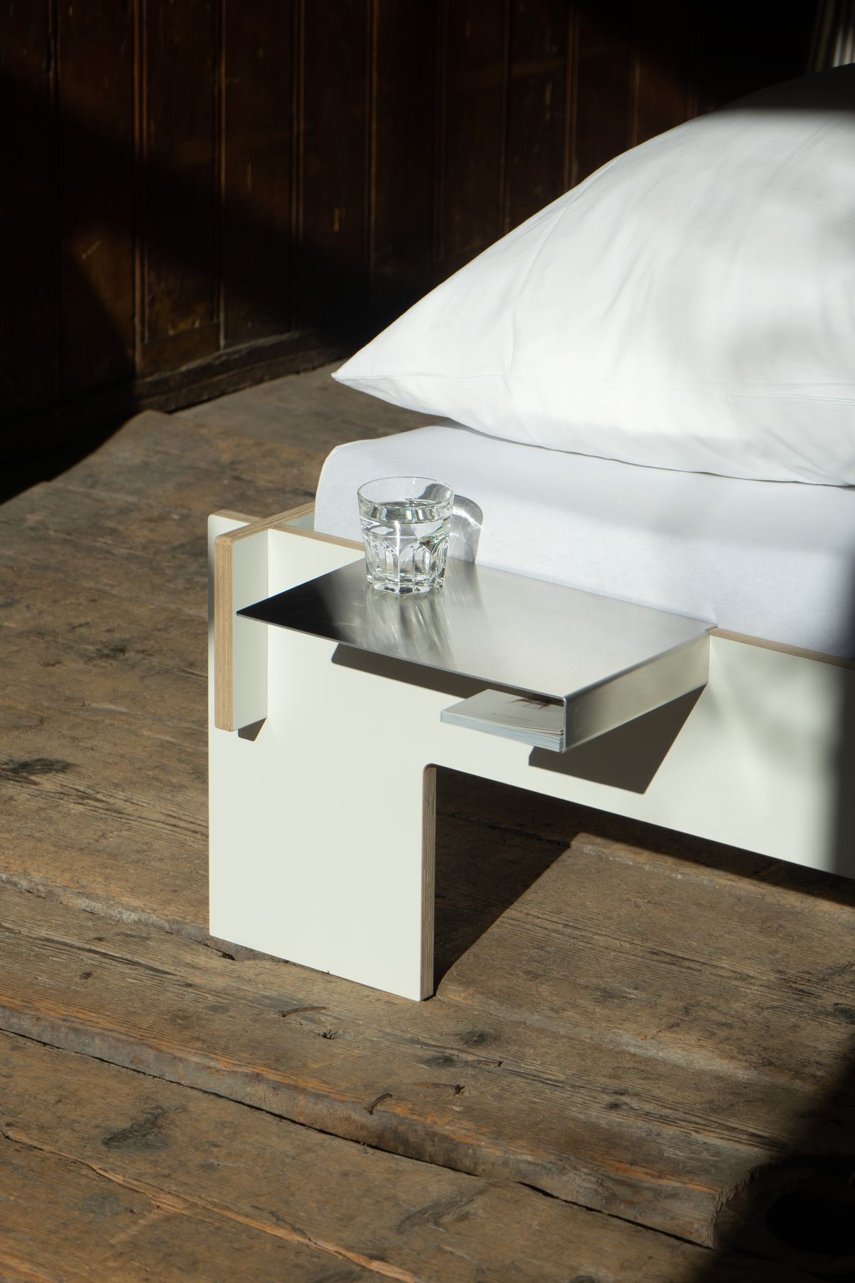 Nils Holger Moormann Bettkante Leicht: Nachttisch mit Glas Wasser am Bett.