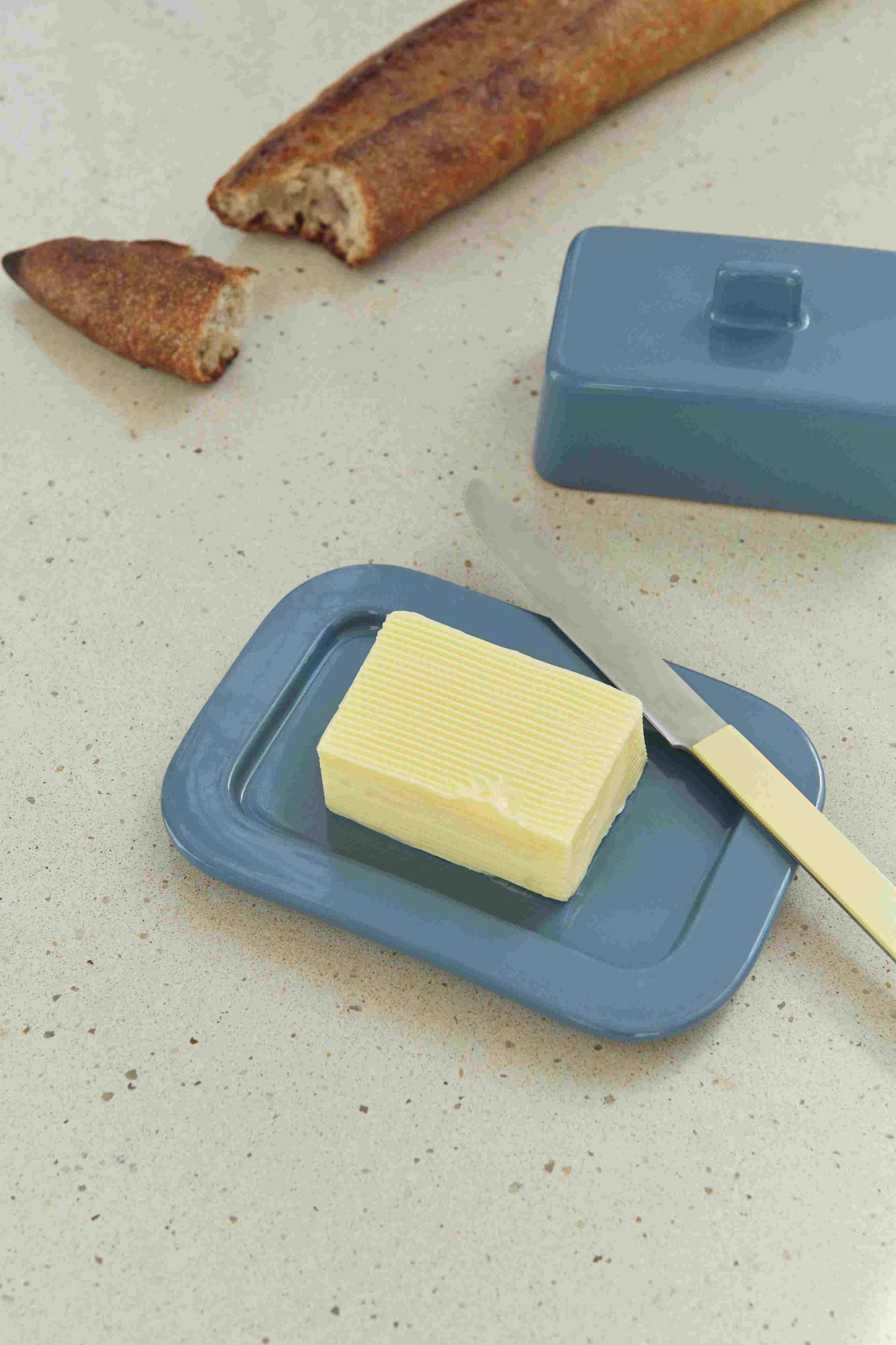 Nahaufnahme der blauen Hay Barro Butterdose mit Butter, Messer und Brot.