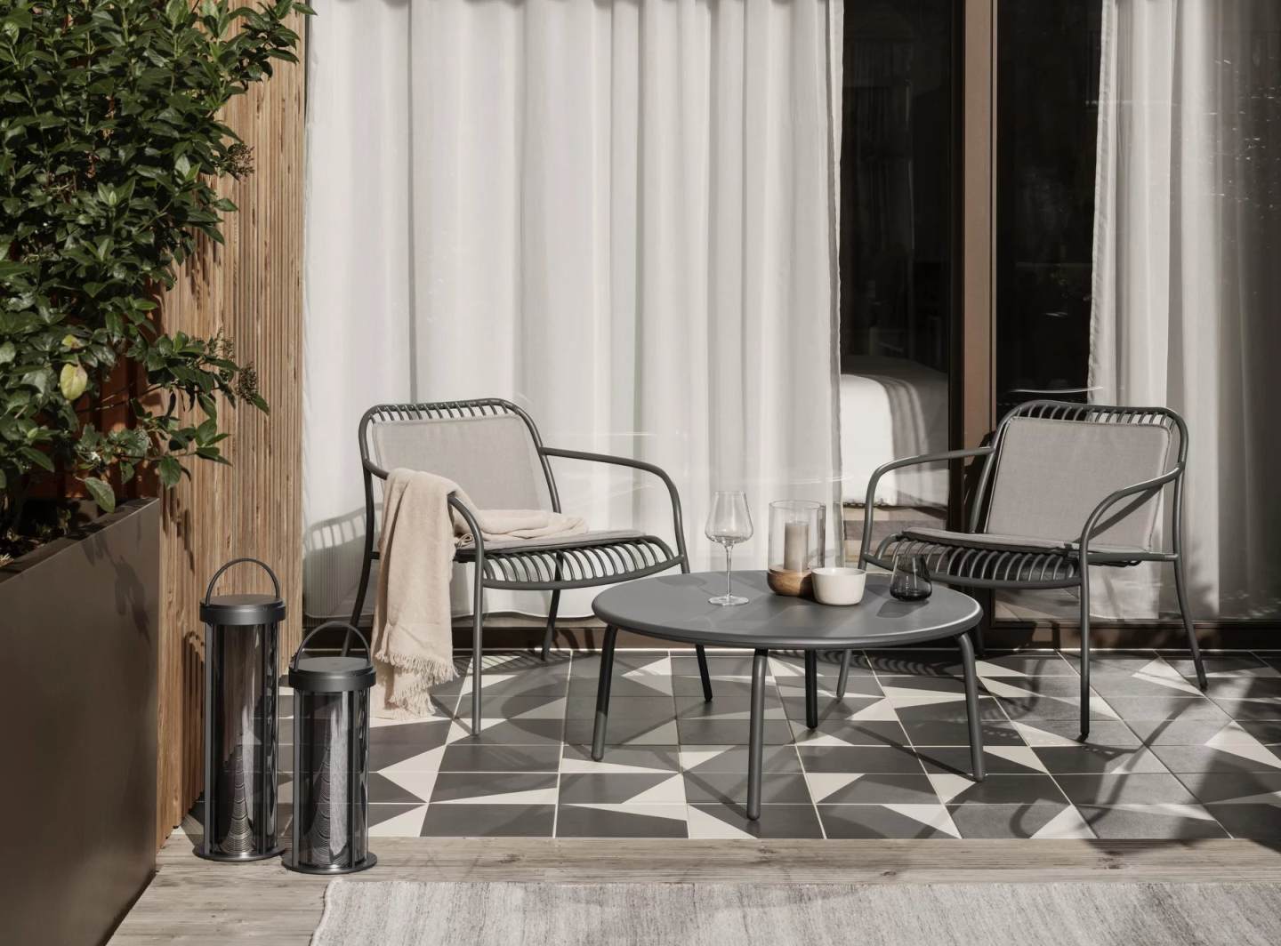Blomus Kiva Rug Outdoor Teppich 140 cm auf einer Terrasse mit Gartenmöbeln.